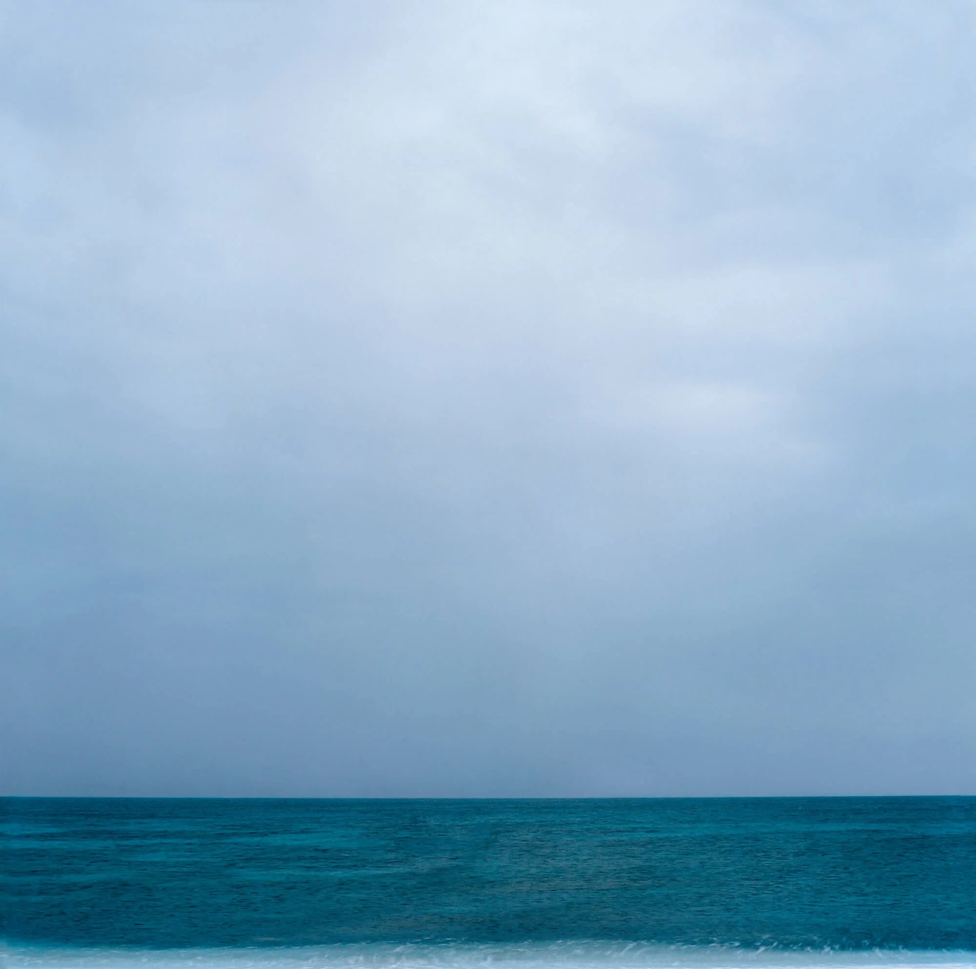 A wide view of the ocean with a cloudy sky overhead.
