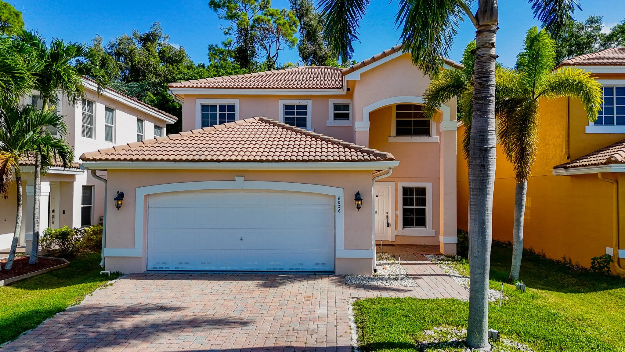 Real Estate Photography services in Ft. Lauderdale featuring interior Bright living room with white sectional sofa, side tables with lamps, large windows showing outdoor view.