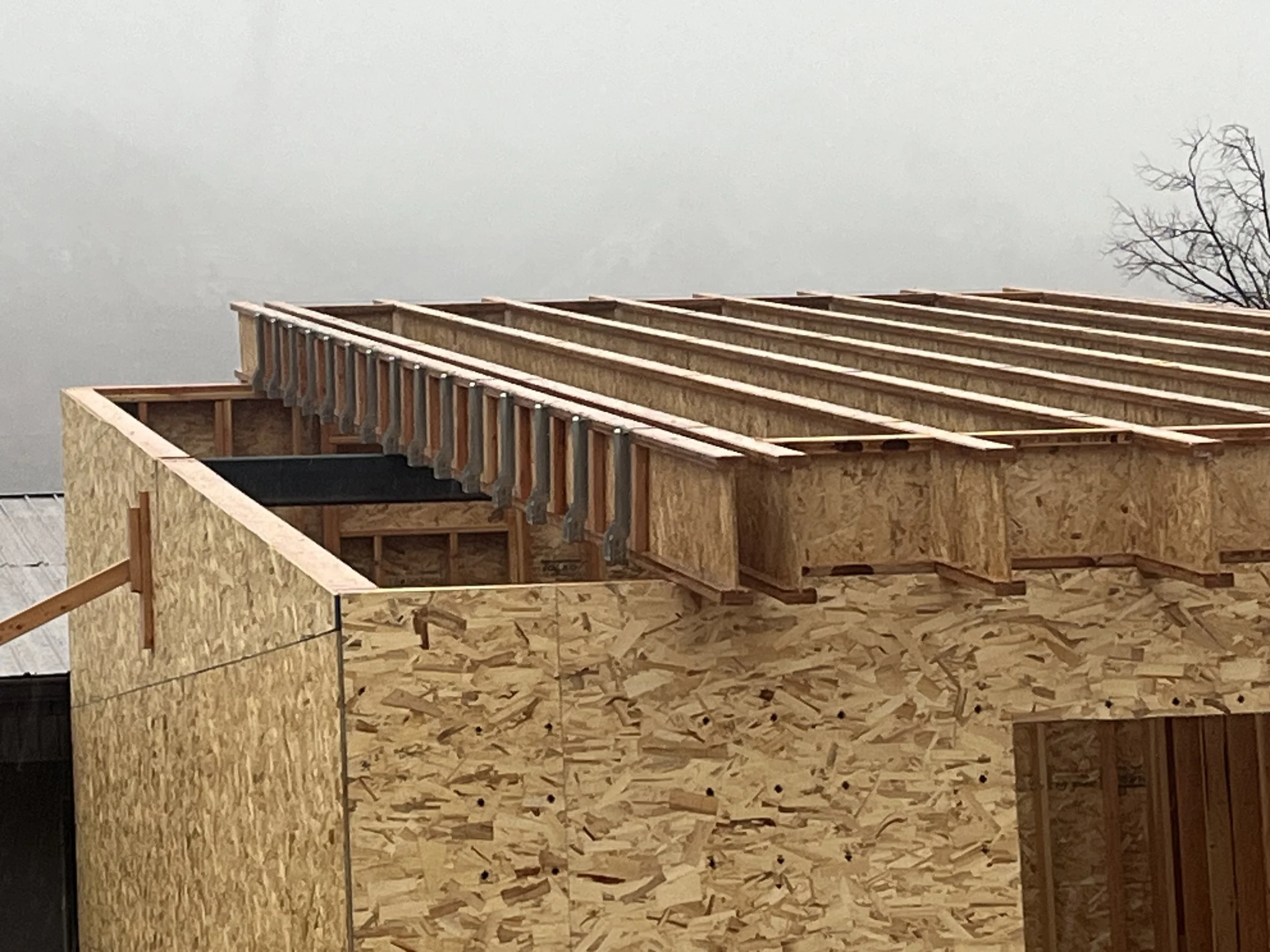 Construction site with a partially built wooden structure on a cloudy sky day.