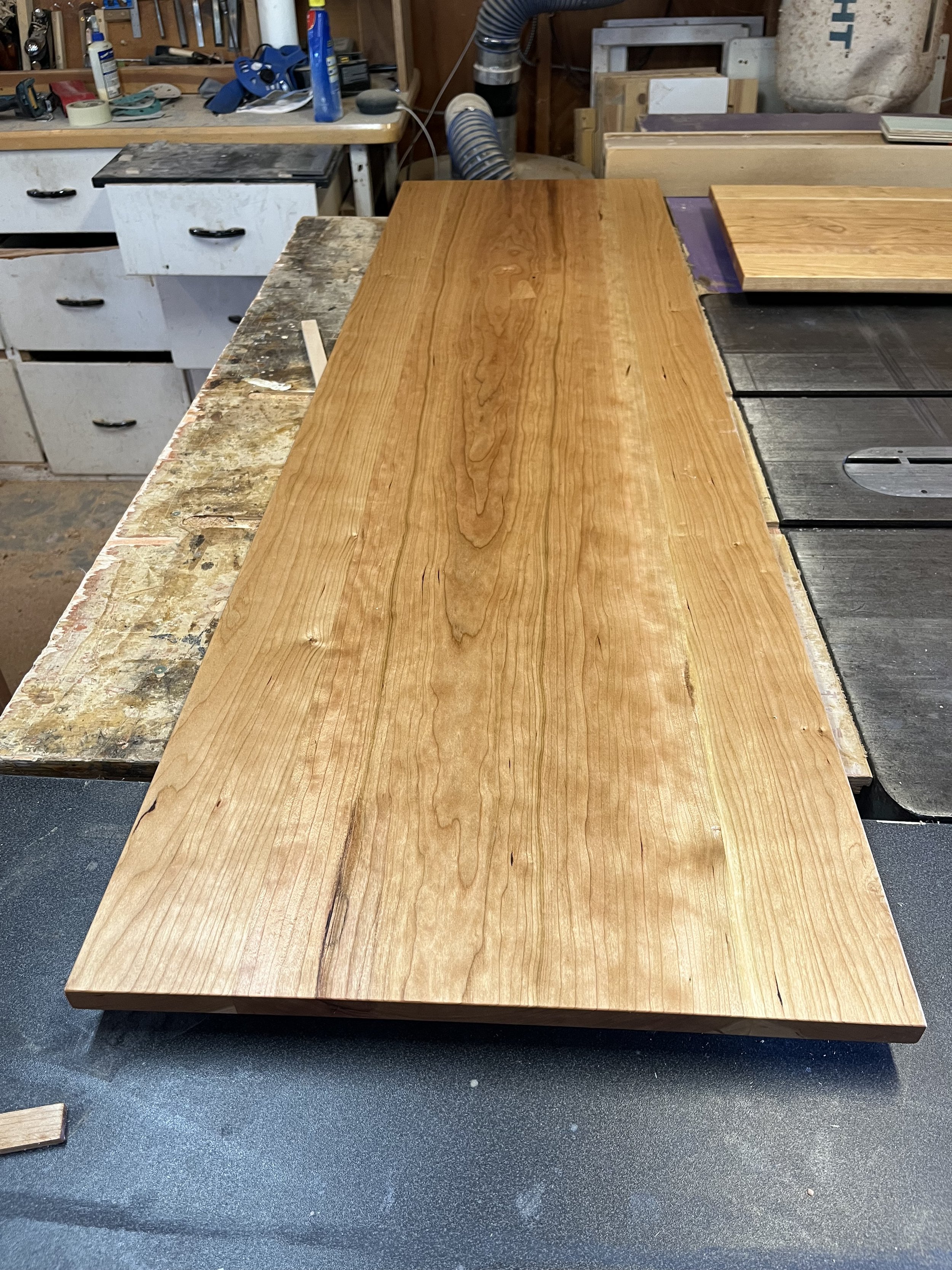 A large wooden plank on a workbench in a woodworking shop.