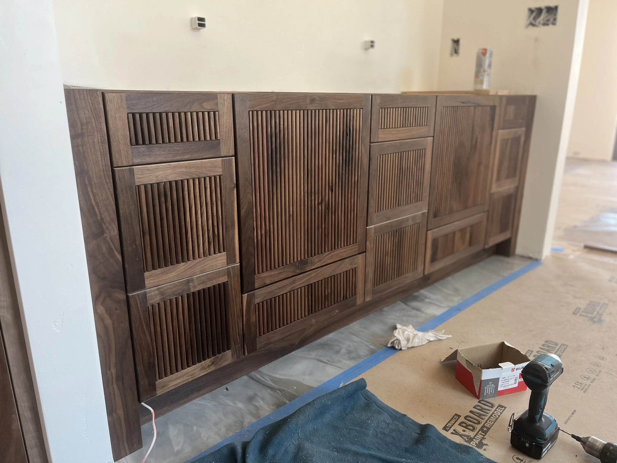A wooden cabinet with a slatted design in a room under construction or renovation.