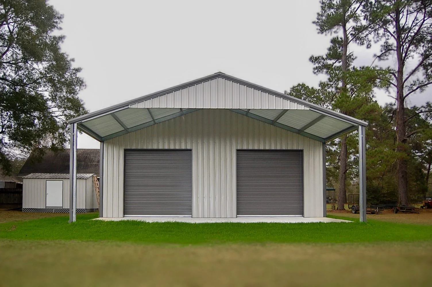 Custom steel garage and workshop building by B&J Metal Buildings featuring dual roll-up garage doors, extended metal awning coverage, and durable residential metal construction in Louisiana.