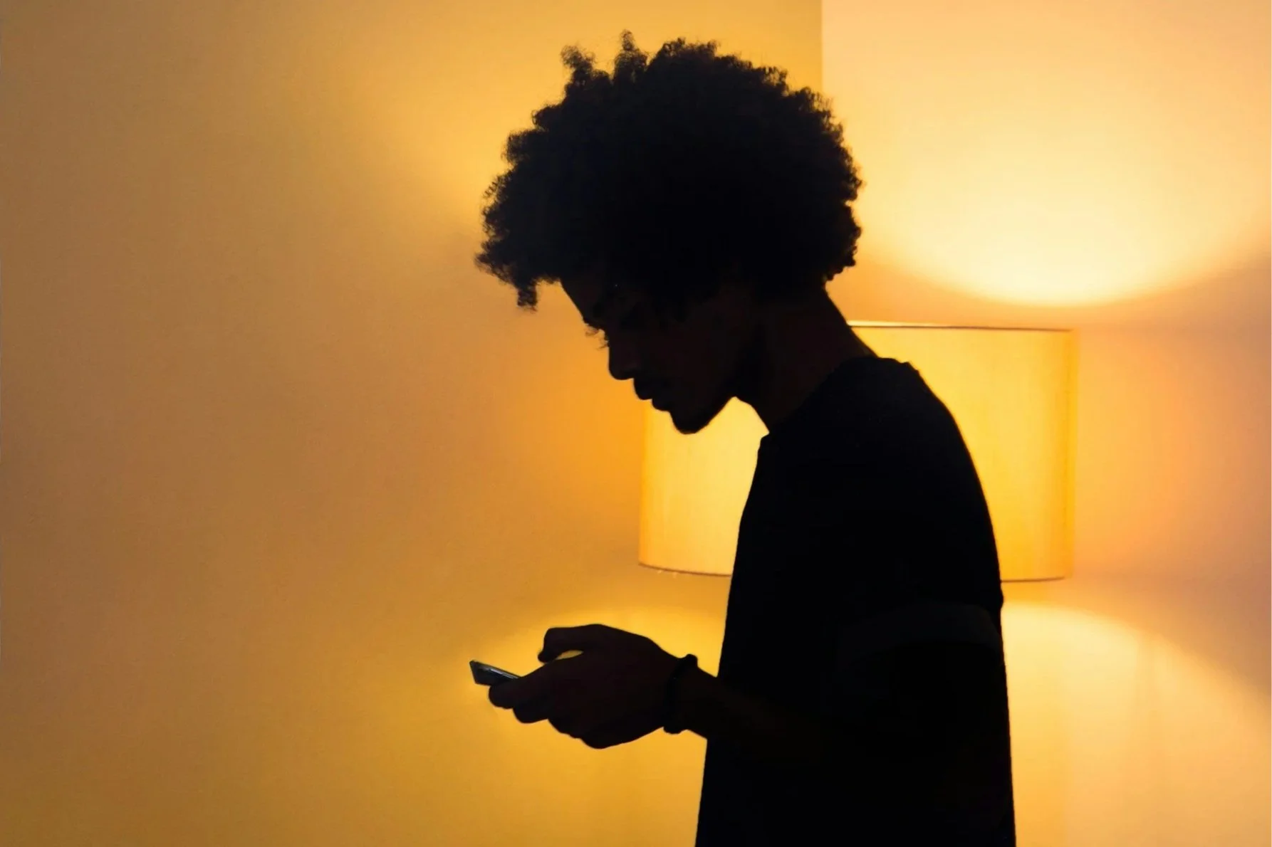 Silhouette of a person looking down at a smartphone