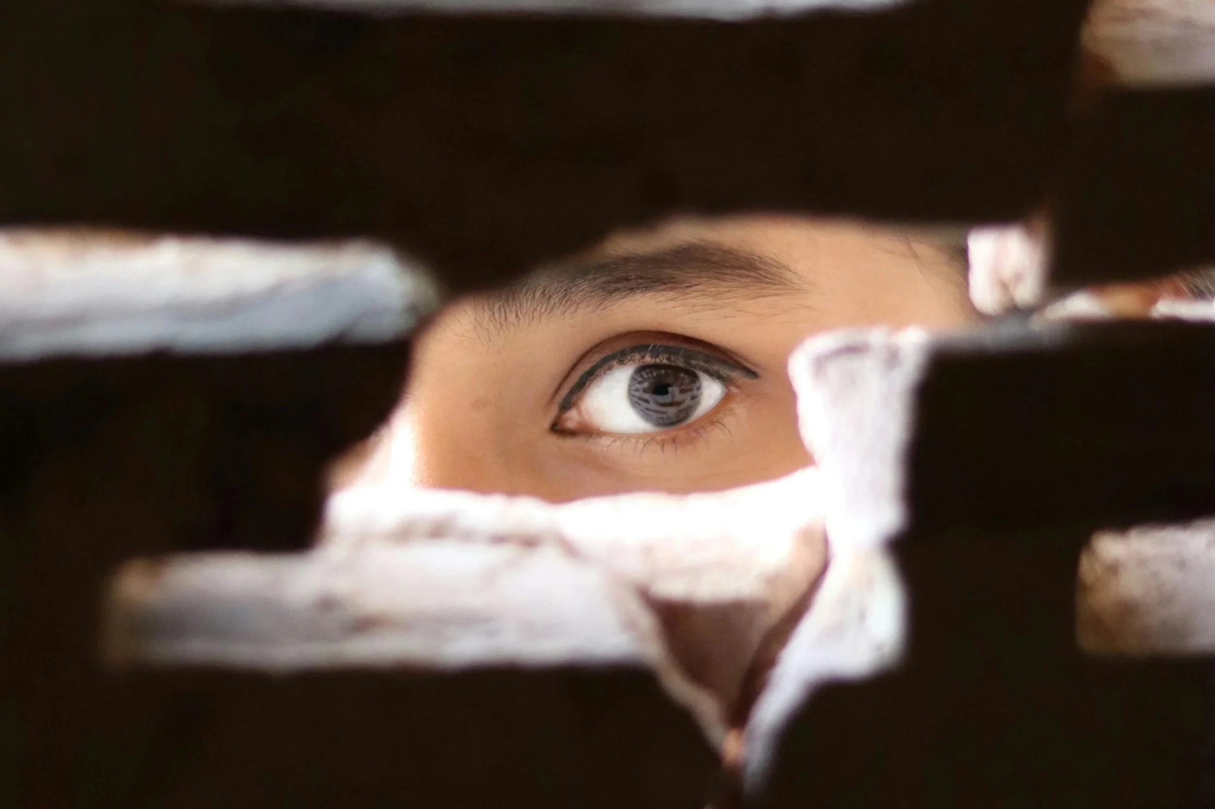 Gentle, feminine eye looking in through a hole in a wall
