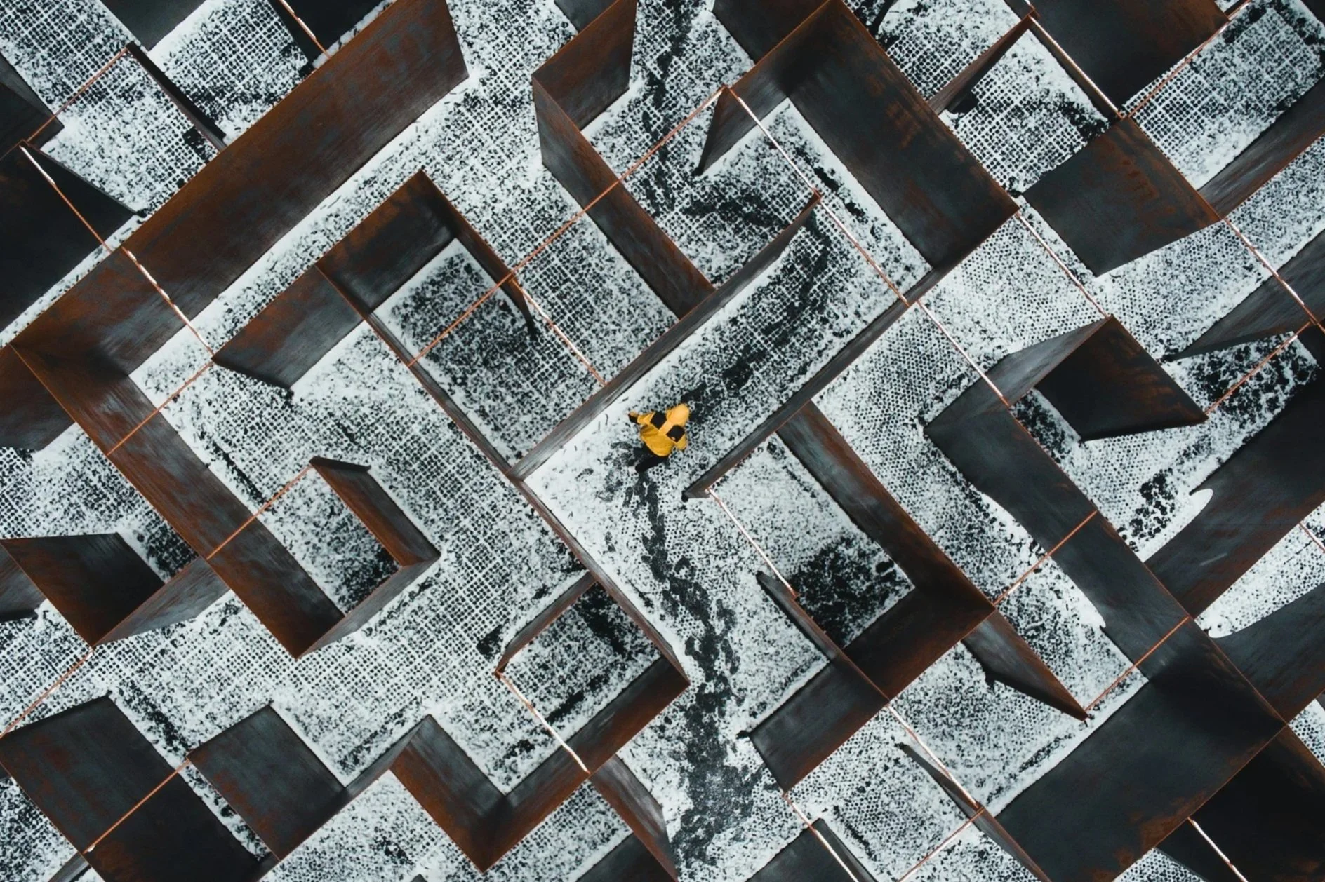 Person in yellow jacket, viewed from above in a maze