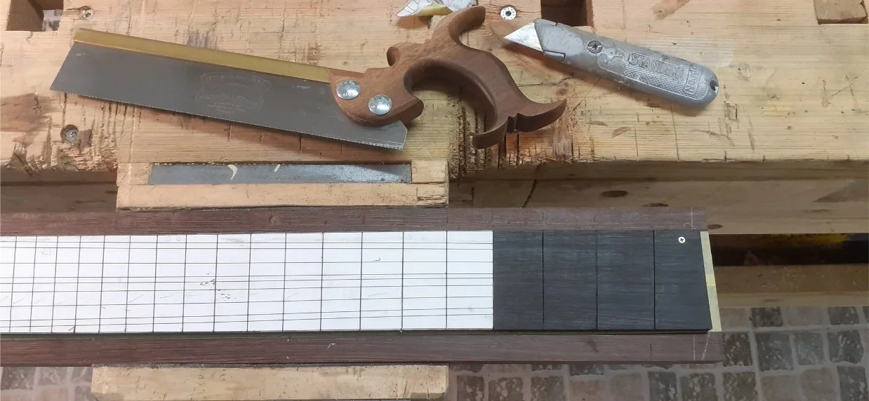 The fret slots were cut with a dovetail saw. This was an inital cut to set the positions of the frets. The final depth of the fret slots was done later, after the fingerboard had been radiused.