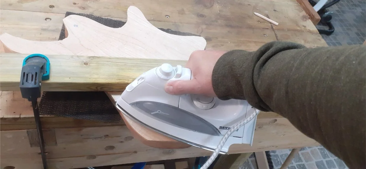 Attempting to pre-bend the maple top with a steam iron. This was partially sucessful. I managed to fix most of the bend into the wood. The remaining bend would be held by the glue.
