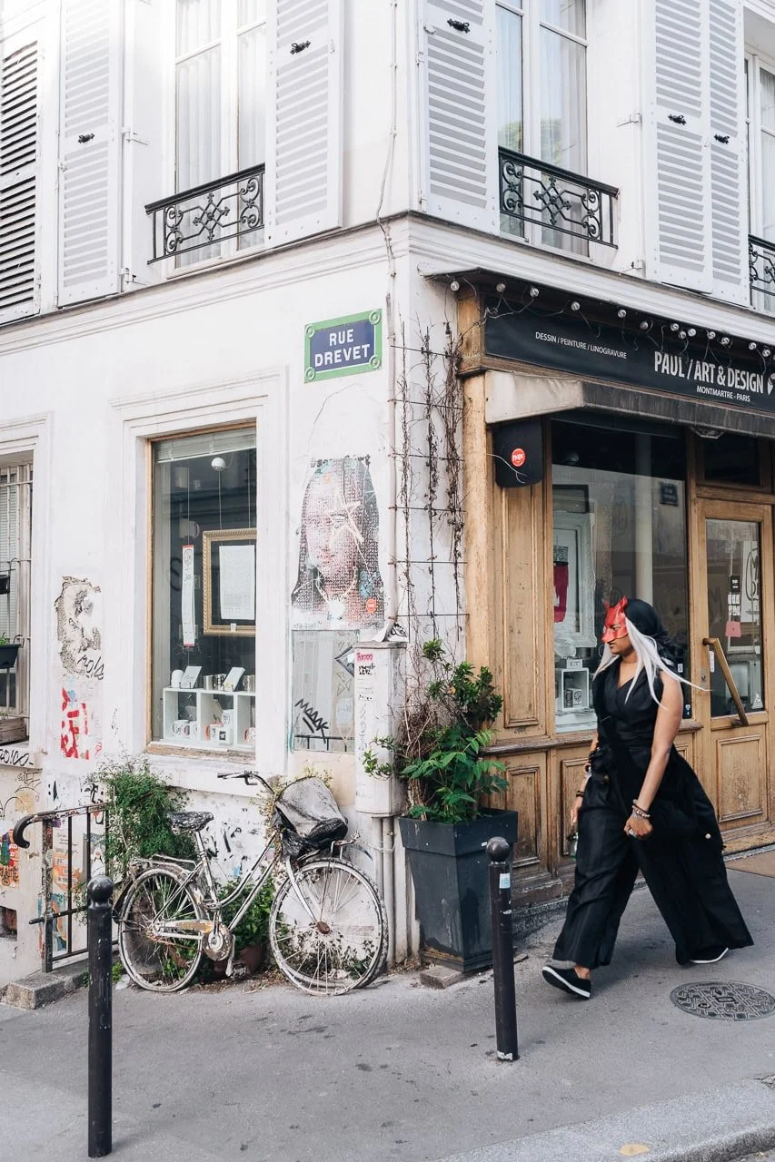 Masked woman walking past an art store in Montmartre, Paris