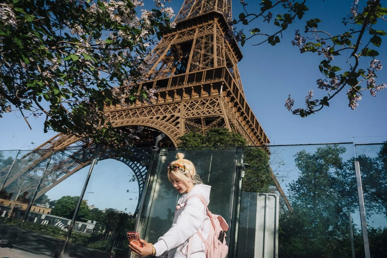 tourist taking a selfie in front of the Eiffel Tower
