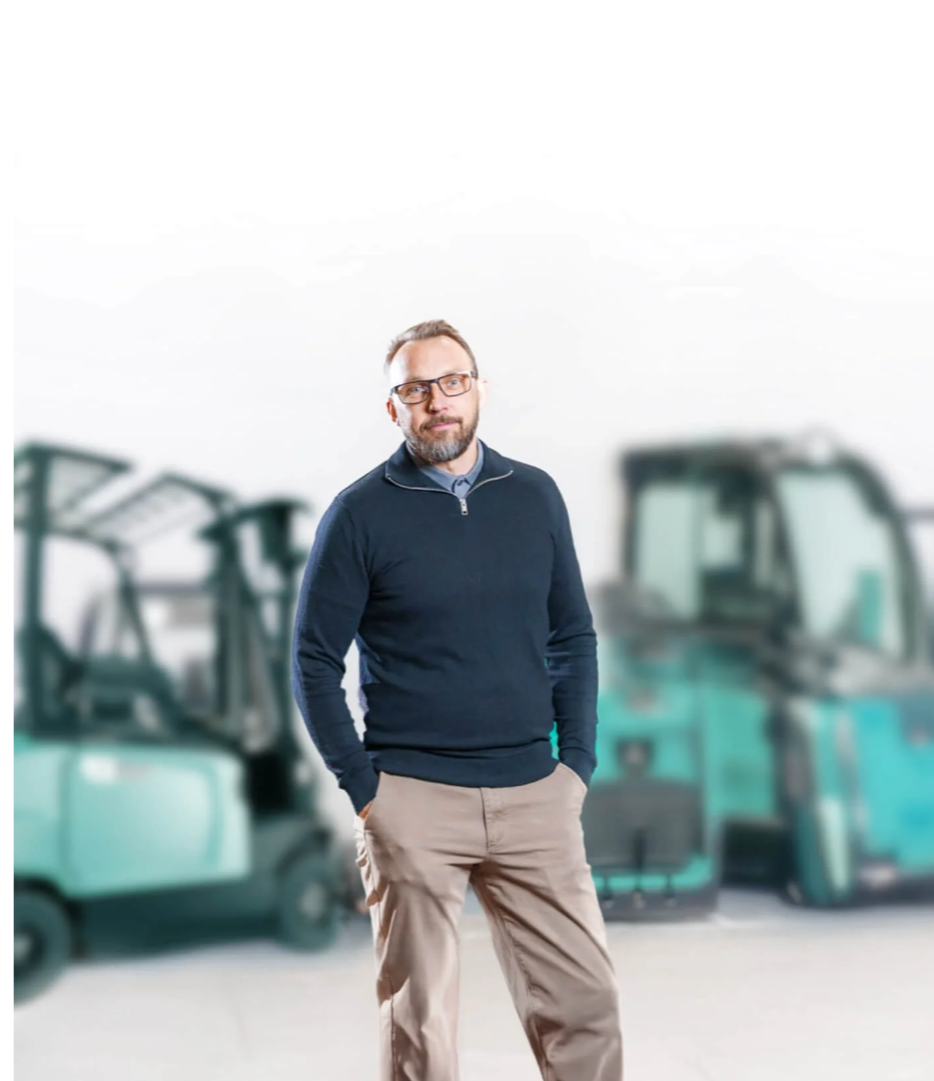 Glad person i mörkblå tröja som står framför turkosa truckar