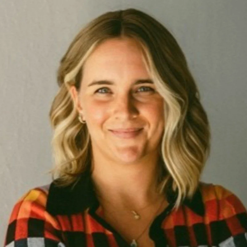 Person with blonde hair wearing a plaid shirt, smiling at the camera.