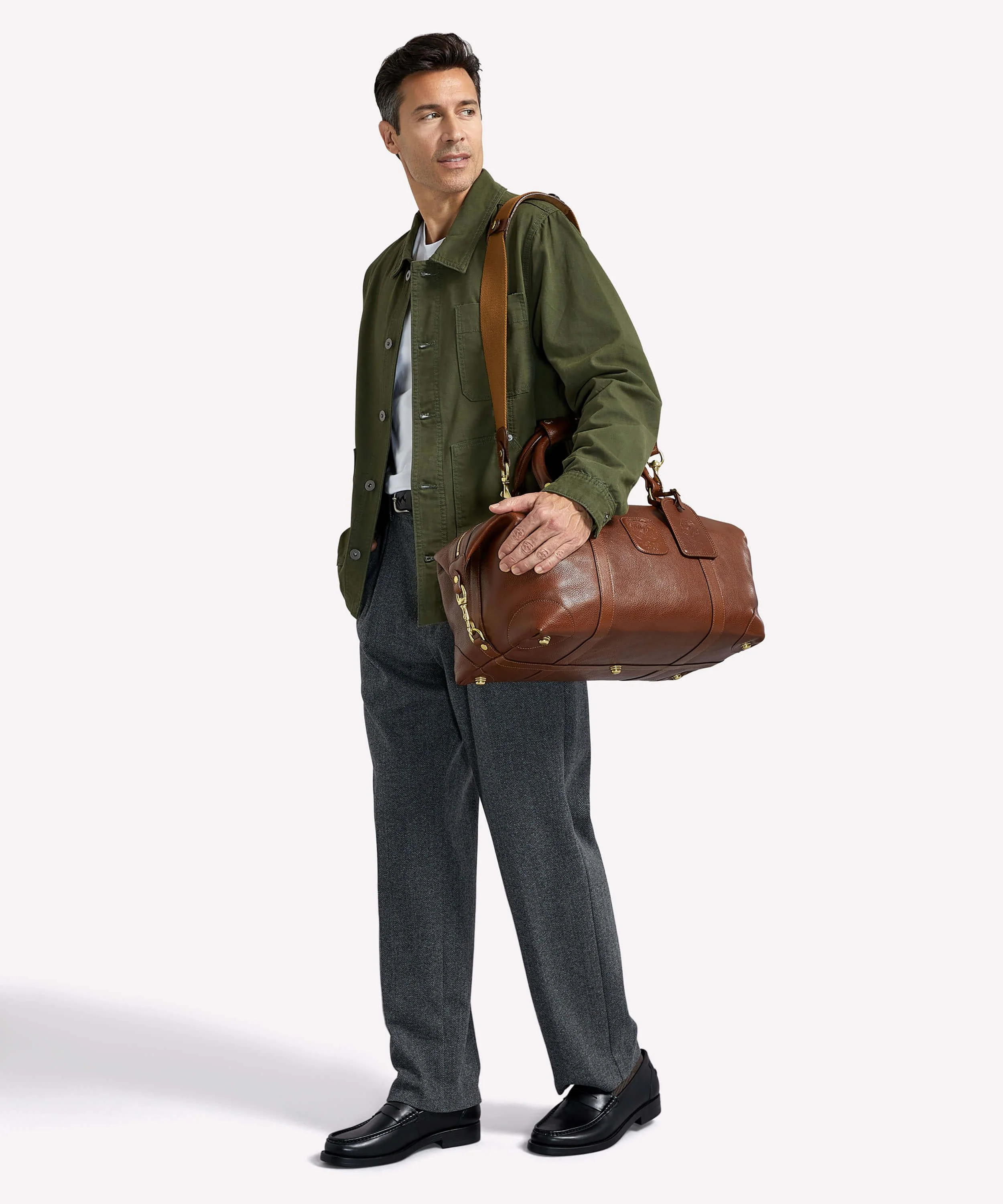 On-model accessories photography of man carrying brown leather duffle bag
