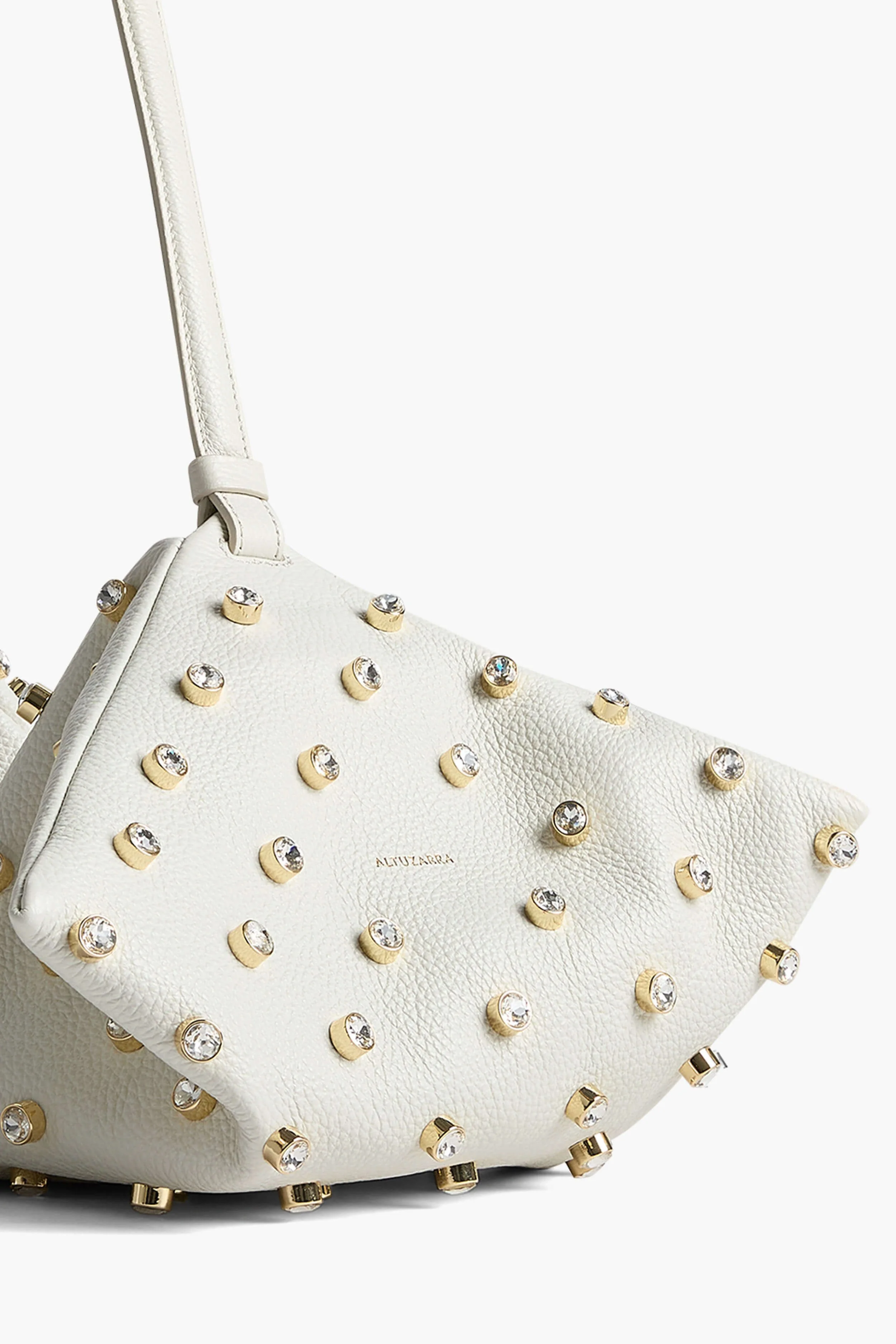 Luxury handbag photography of white studded crossbody bag showing hardware detail