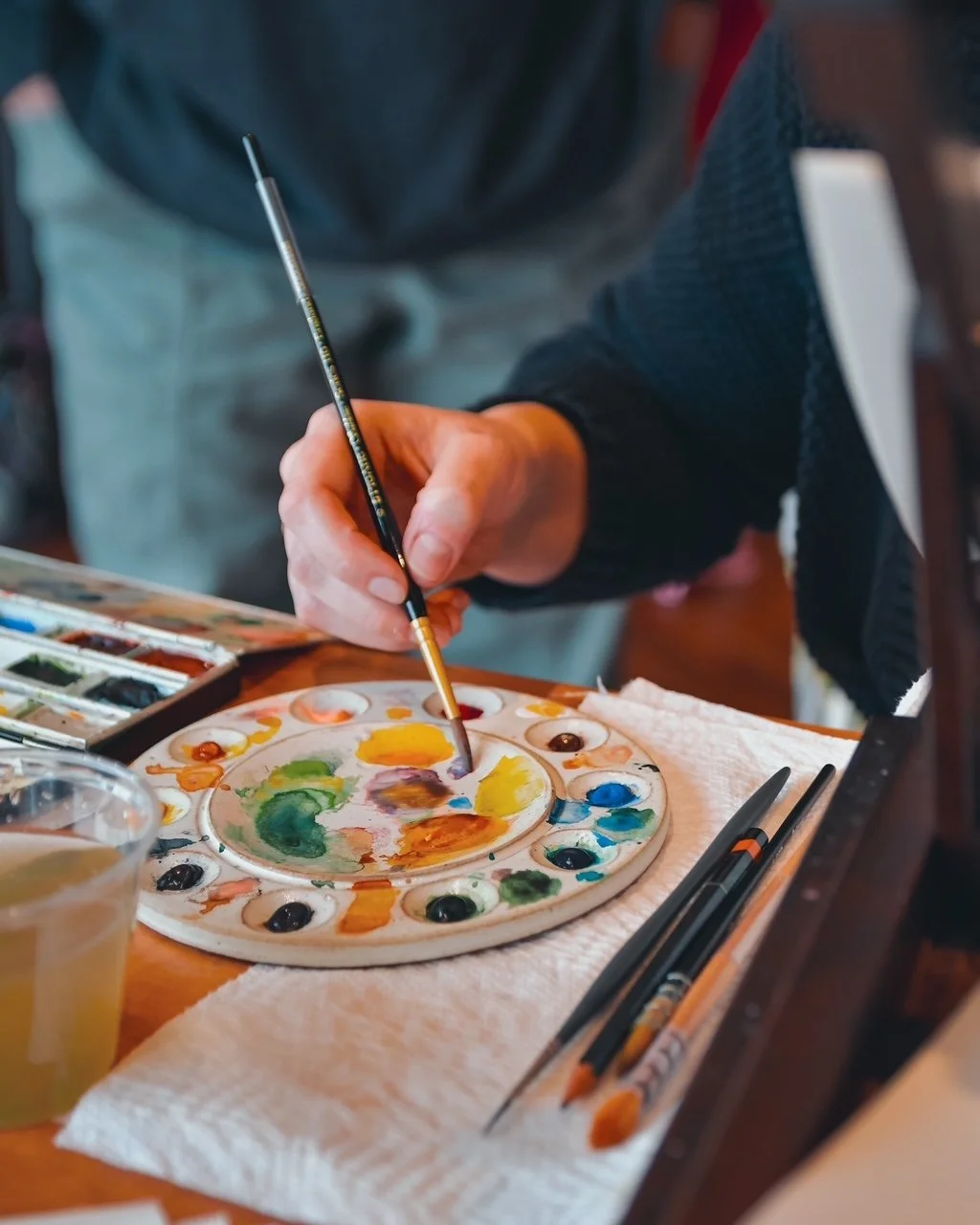 artist mixing watercolor paint on a ceramic palette