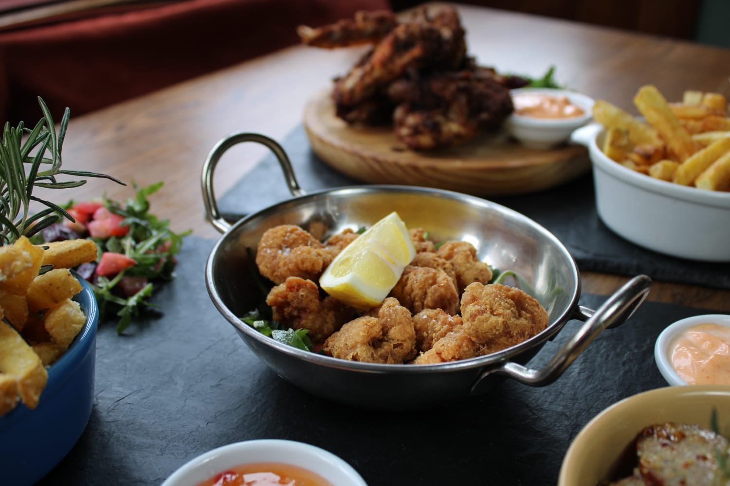 Crispy salt and pepper squid served at The Anchor Inn in Henley, featuring golden-fried tender squid pieces seasoned with aromatic spices, garnished with fresh herbs and lemon wedges, presented on a rustic plate in a charming pub atmosphere.