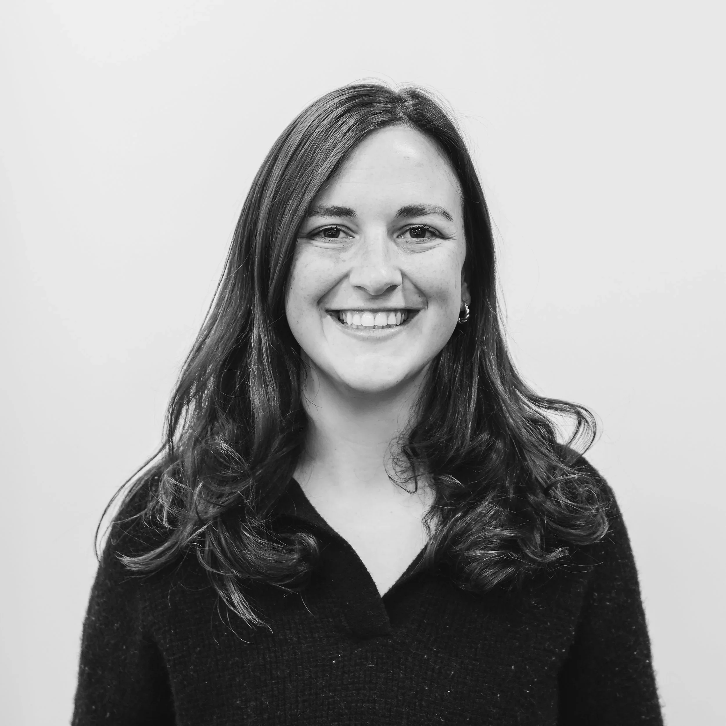 Smiling woman with curly hair wearing a floral top in black and white