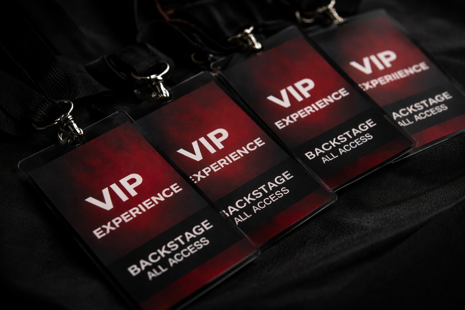 Three VIP backstage access badges with black lanyards on a black surface.