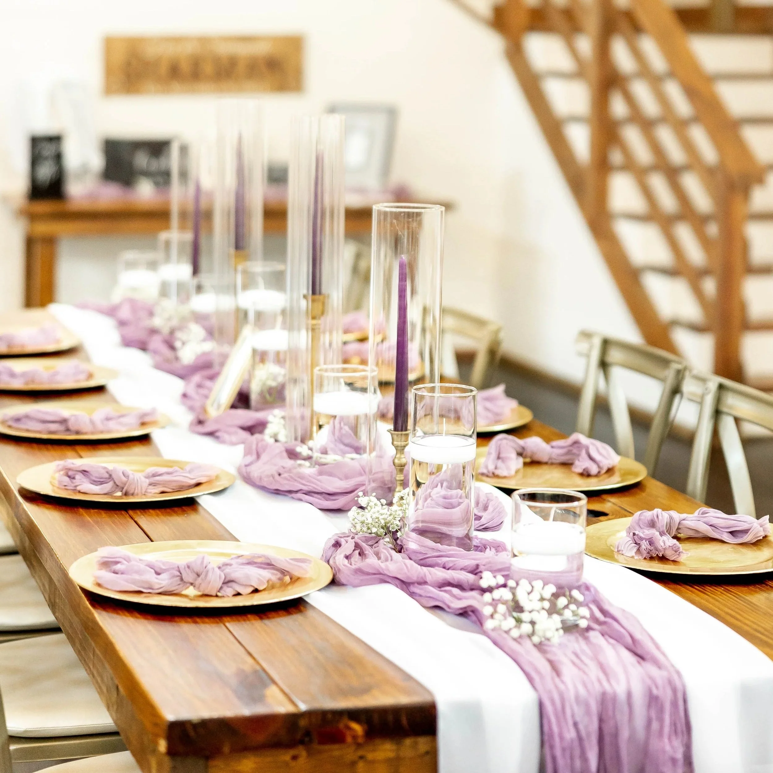 Lavendar table runner with plum candles and gold chargers.