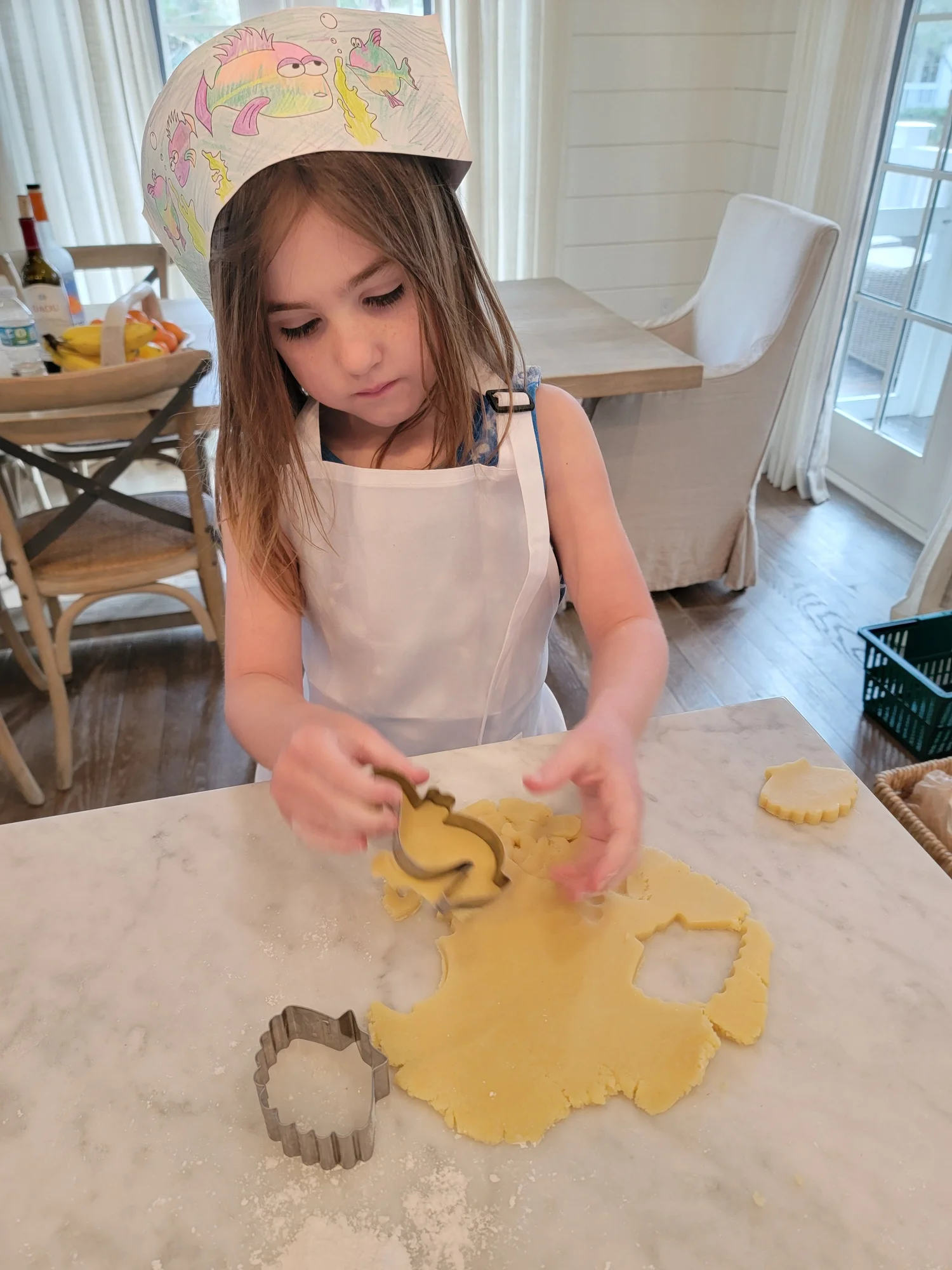 Little girl in a chef's hat cutting cookie dough at a family cooking class