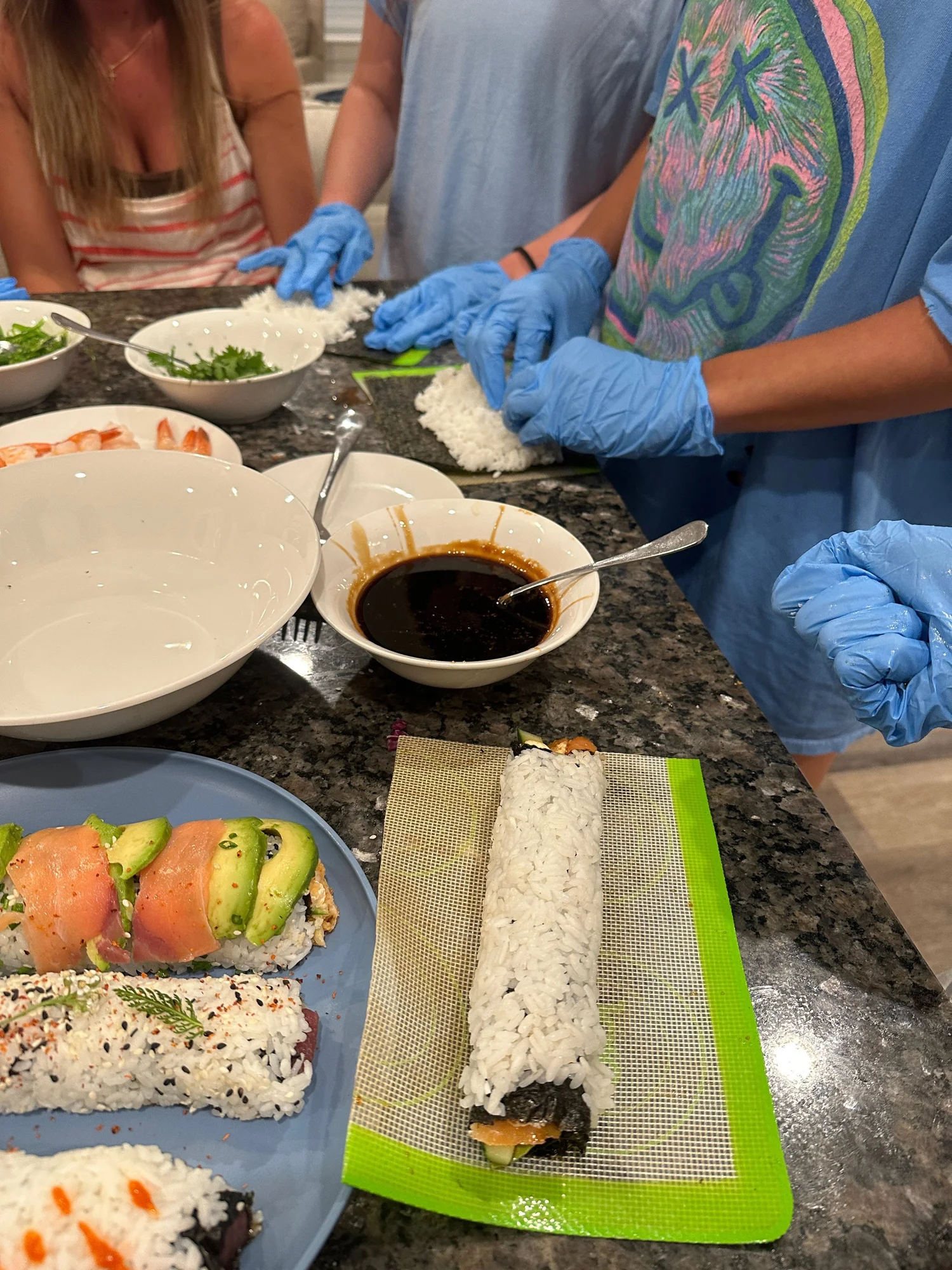Guests in gloves rolling salmon sushi at a Chef Jojo cooking class