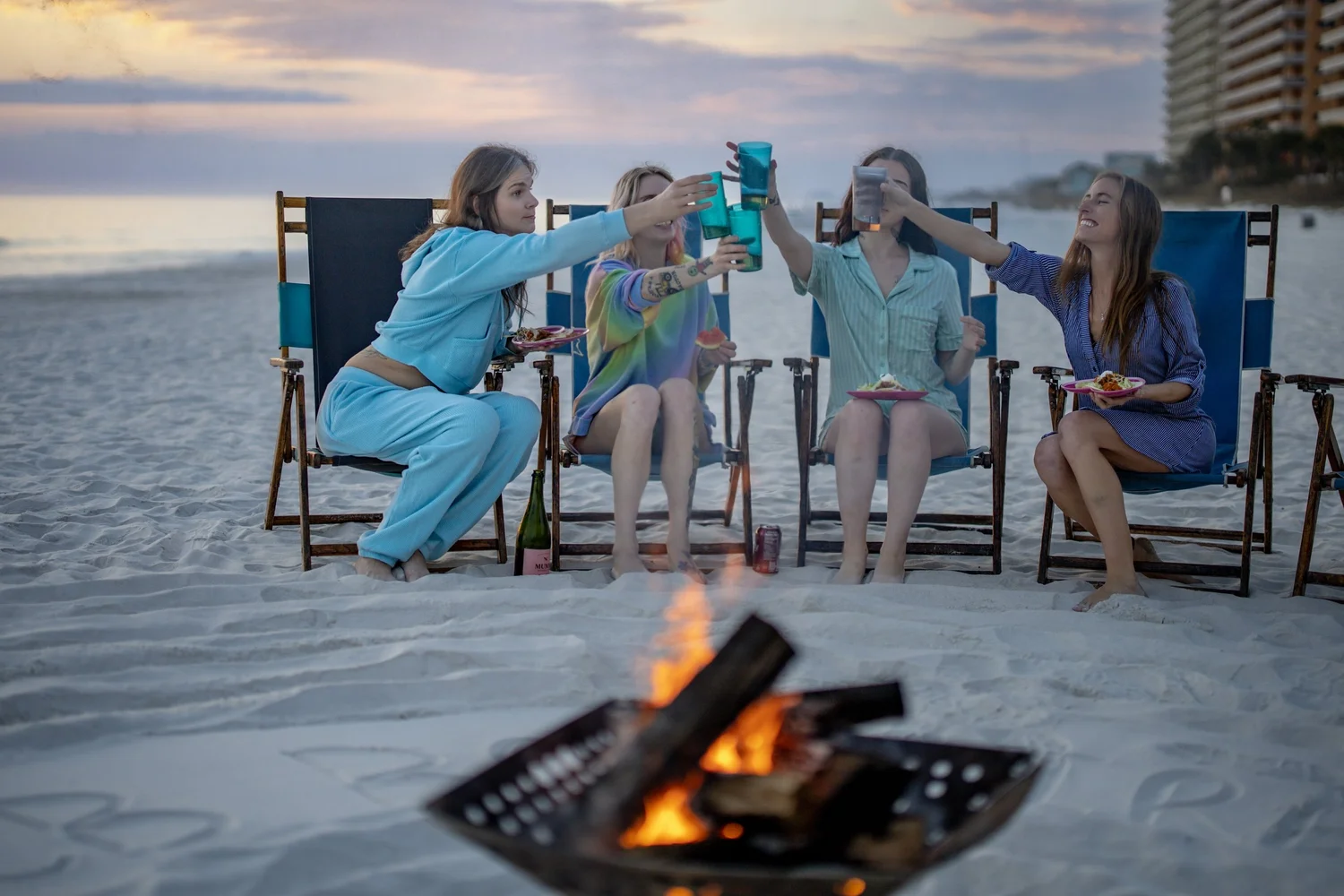Friends toasting in beach chairs around a permitted bonfire on 30A