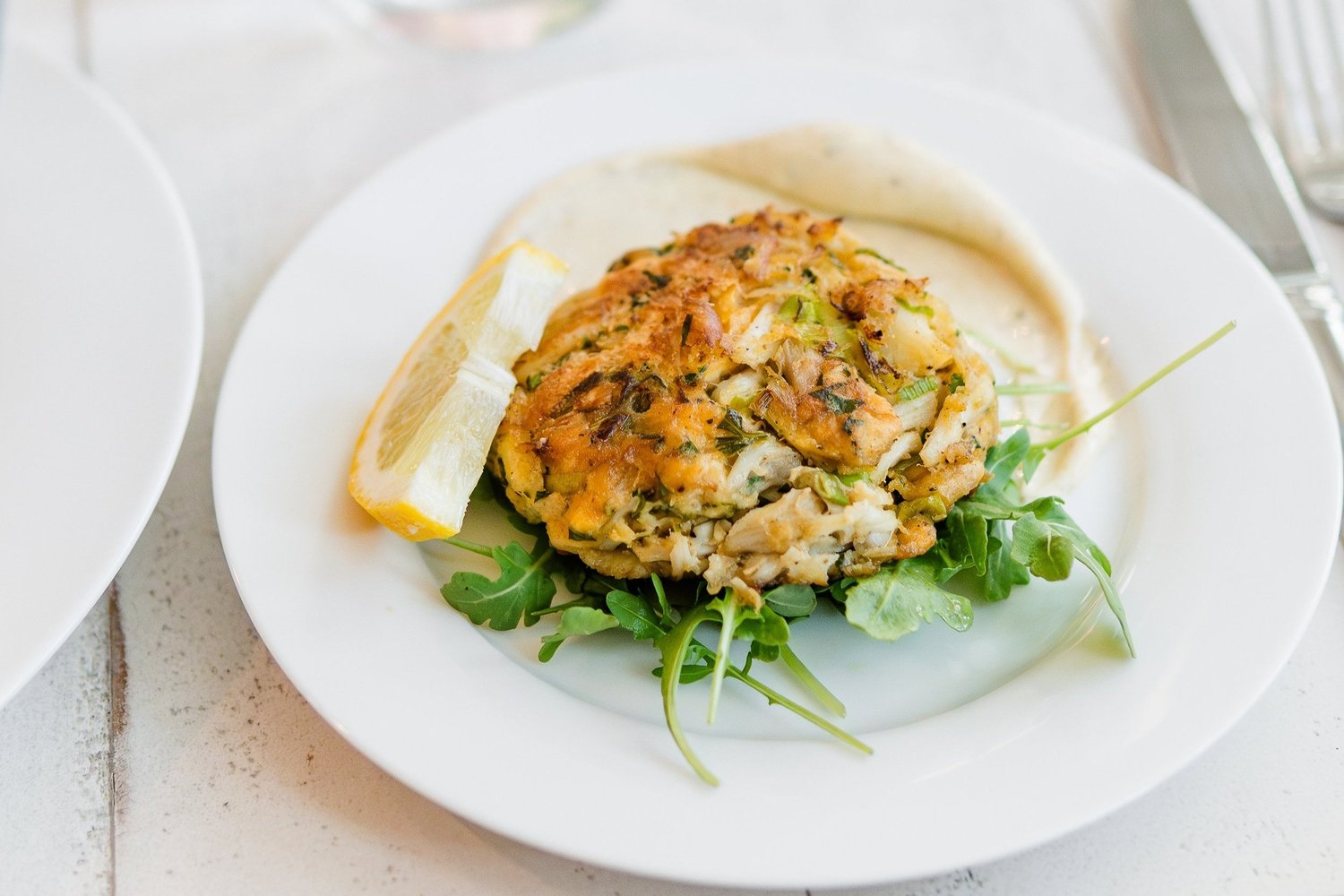 Golden crab cake with lemon and arugula, plated for a 30A dinner