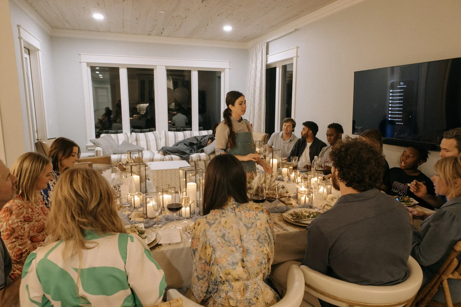 Guests around a candlelit dining table in a 30A vacation home during a private chef dinner