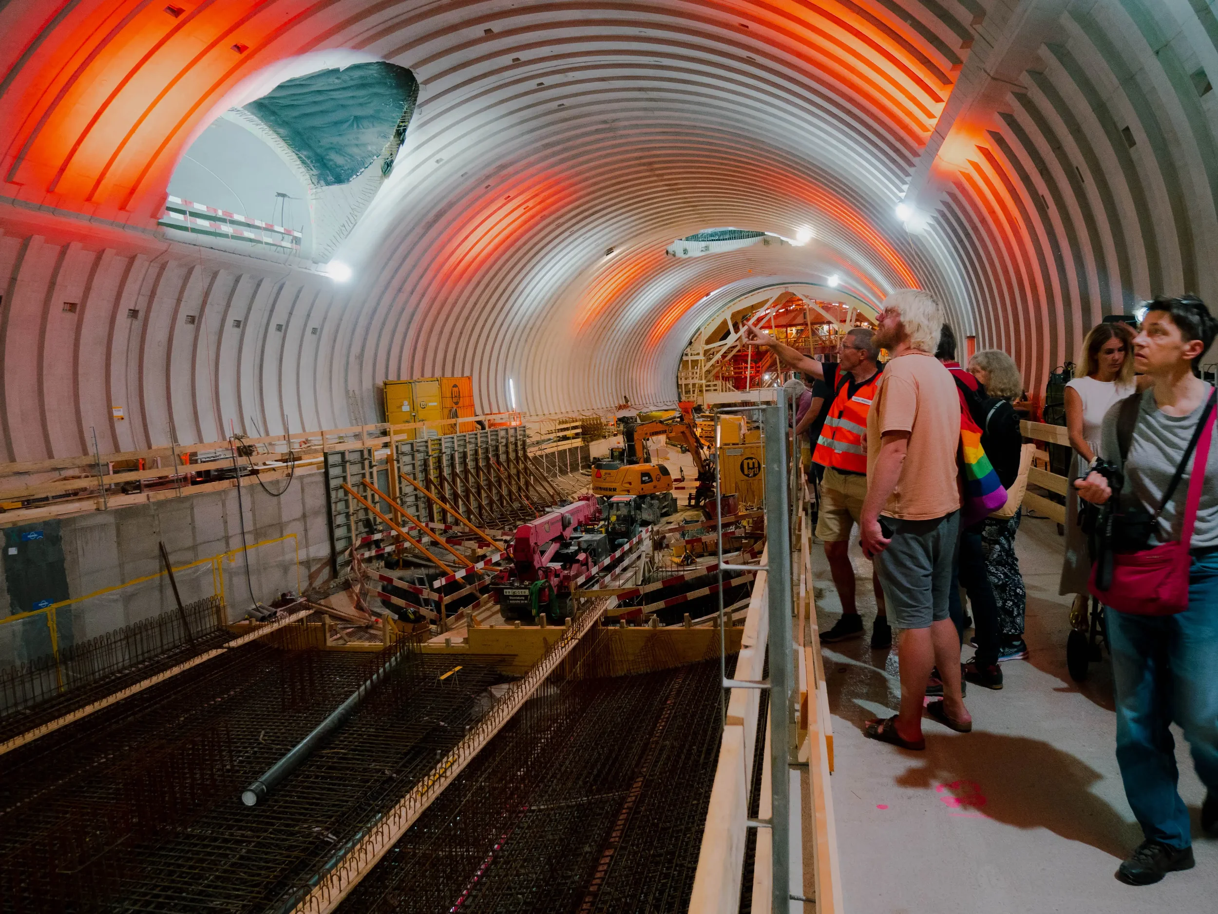 Menschenbesucher in einer Tunnelbaustelle, die den Baufortschritt beobachten, mit Baugeräten und Beleuchtung