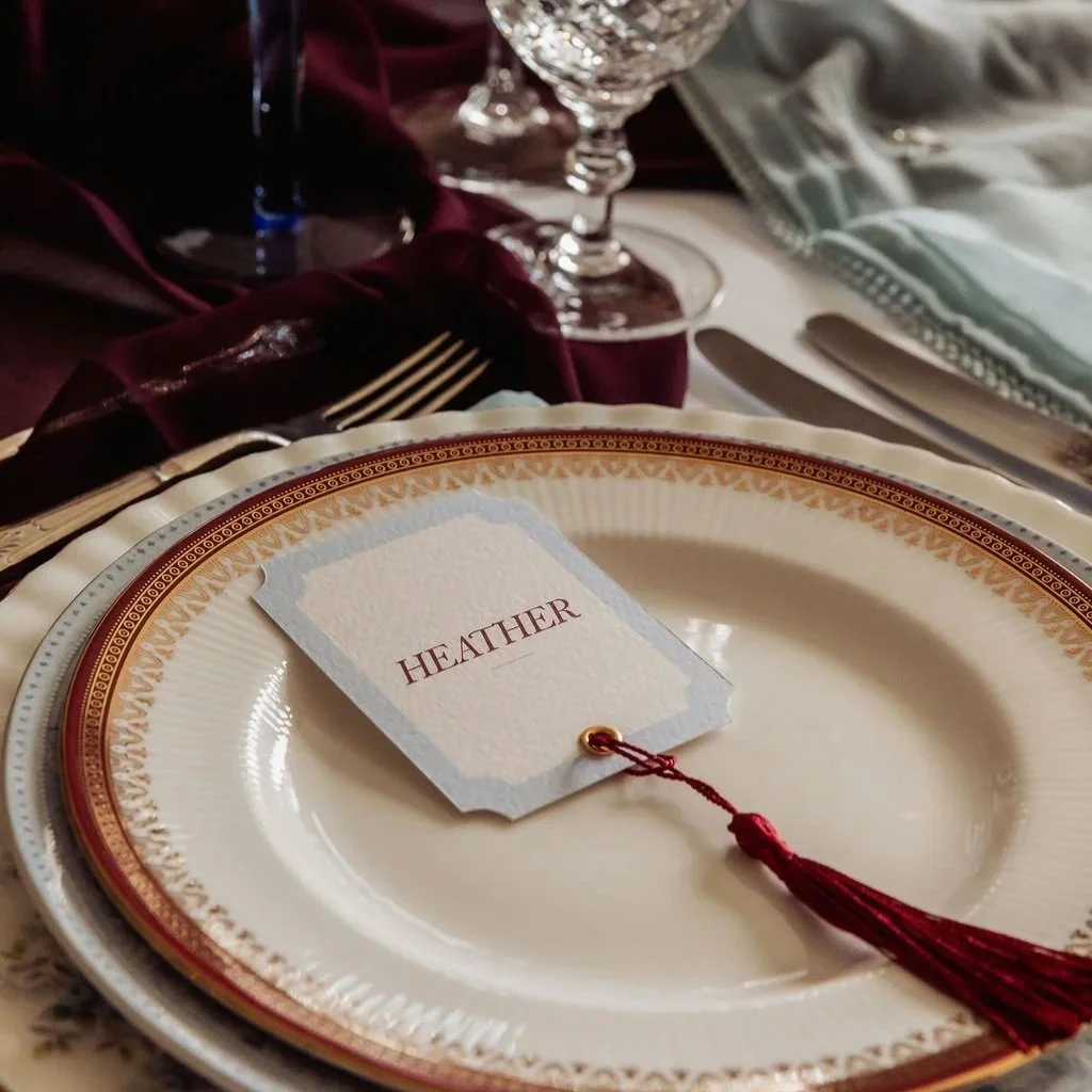 Luxury wedding place cards in ivory and powder blue, adorned with burgundy tassels. Stationery designed by Carrie at Honey Bee Mine, and captured in the Scottish Highlands.