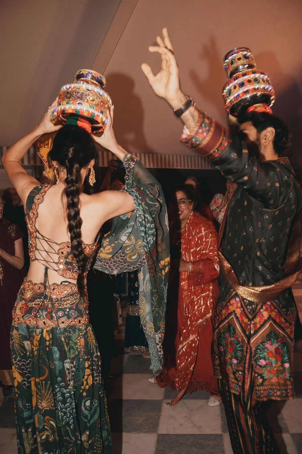 People participating in a traditional Sikh dance, holding decorated pots on their heads, dressed in colourful attire at a cultural celebration.