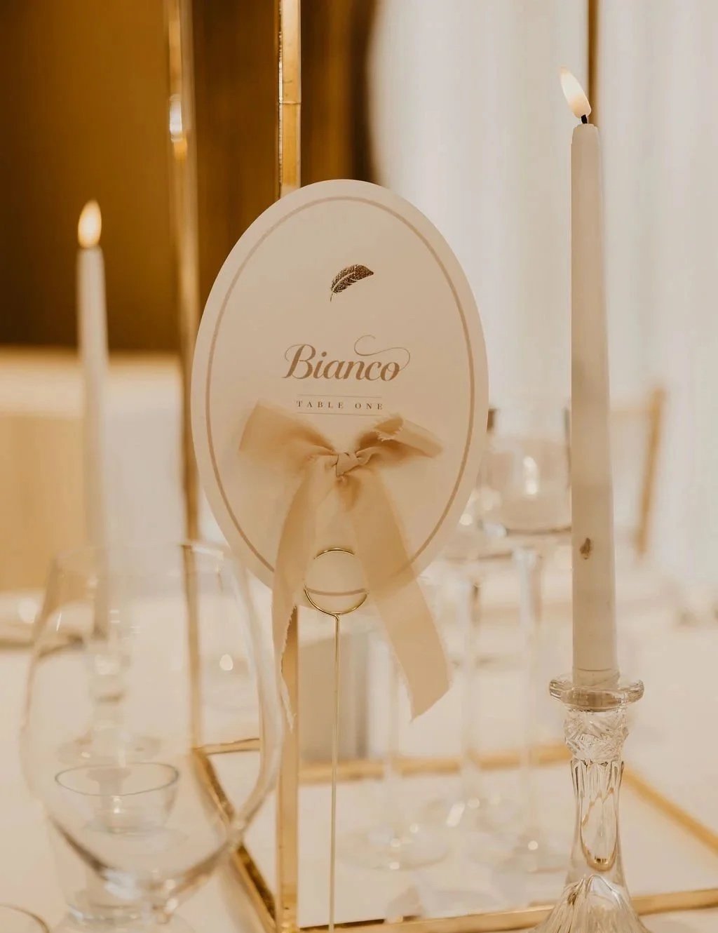 La Plume oval table number with ribbon and gold foil, styled for a wedding at Wivenhoe House. Designed by Honey Bee Mine.