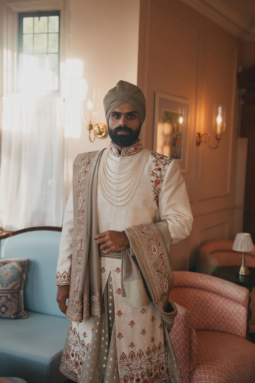 A man in traditional Indian wedding attire standing indoors at Kin House.