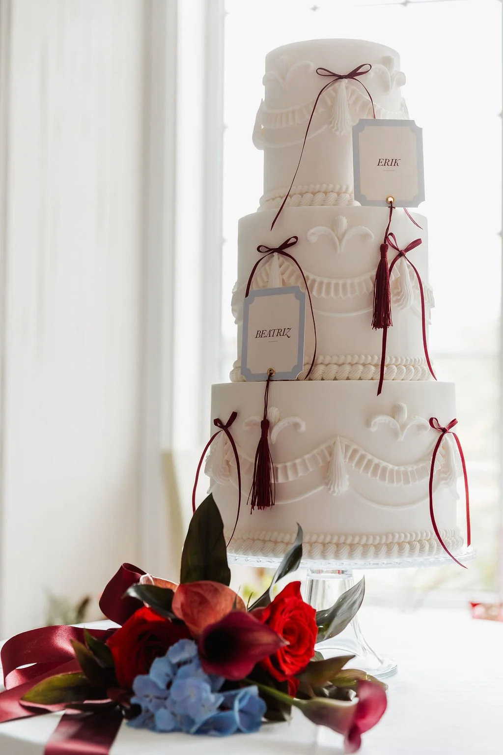 Luxury wedding place cards with burgundy tassels arranged alongside a stunning wedding cake. Place cards designed by Carrie at Honey Bee Mine, and captured in the Scottish Highlands.