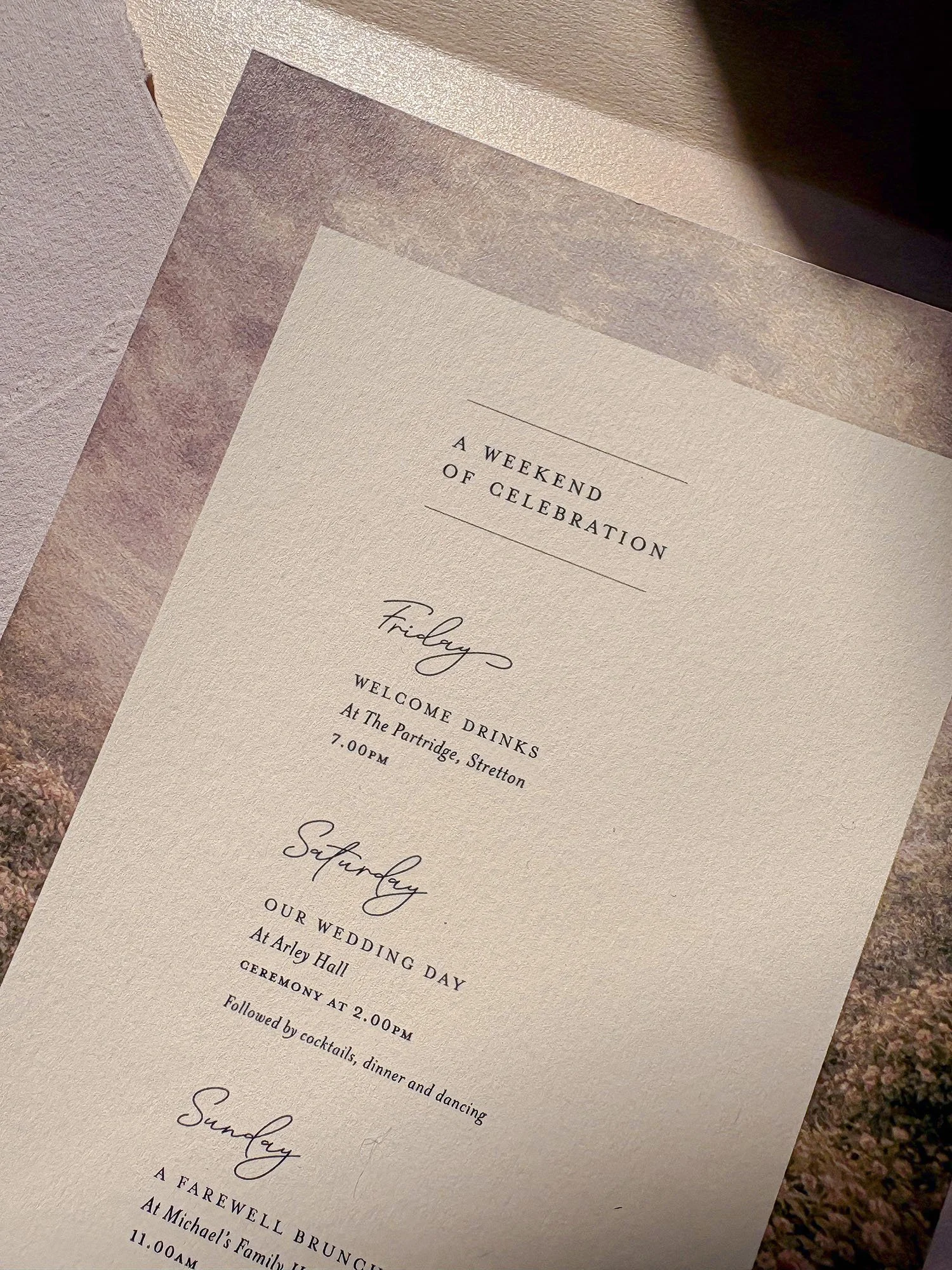Close-up of rose and ivory wedding invitations with vintage-style ribbon at Arley Hall & Gardens.