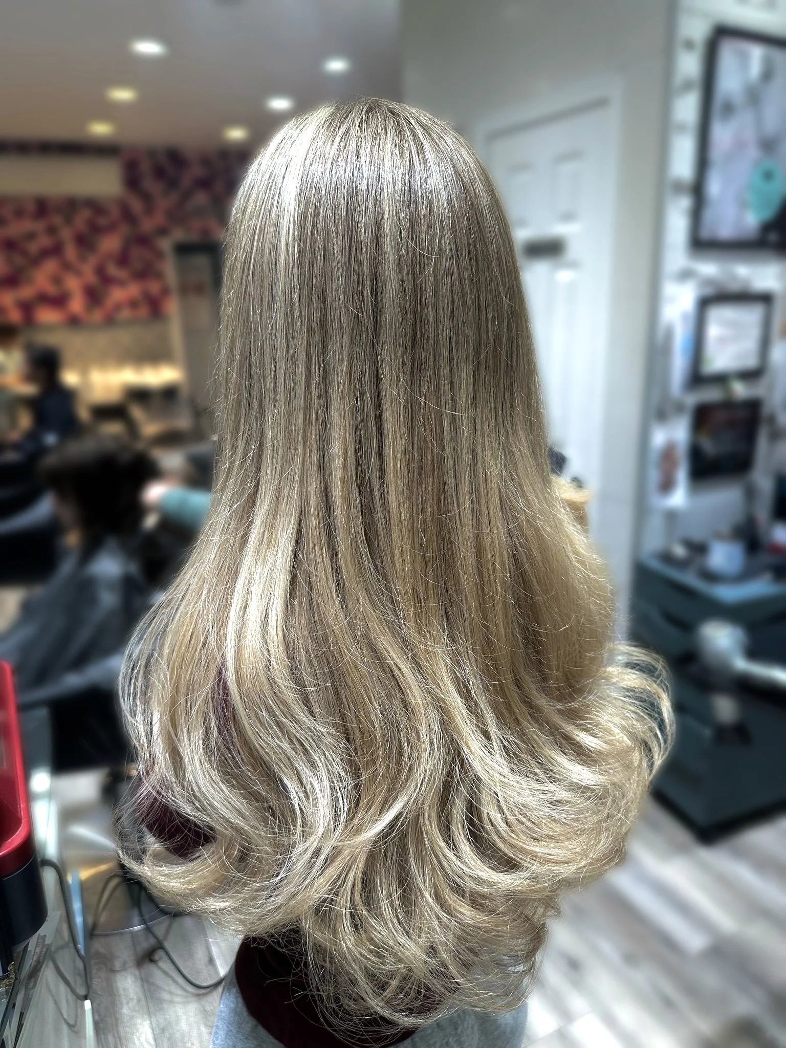 Back view of long, layered blonde hair with soft waves in a hair salon