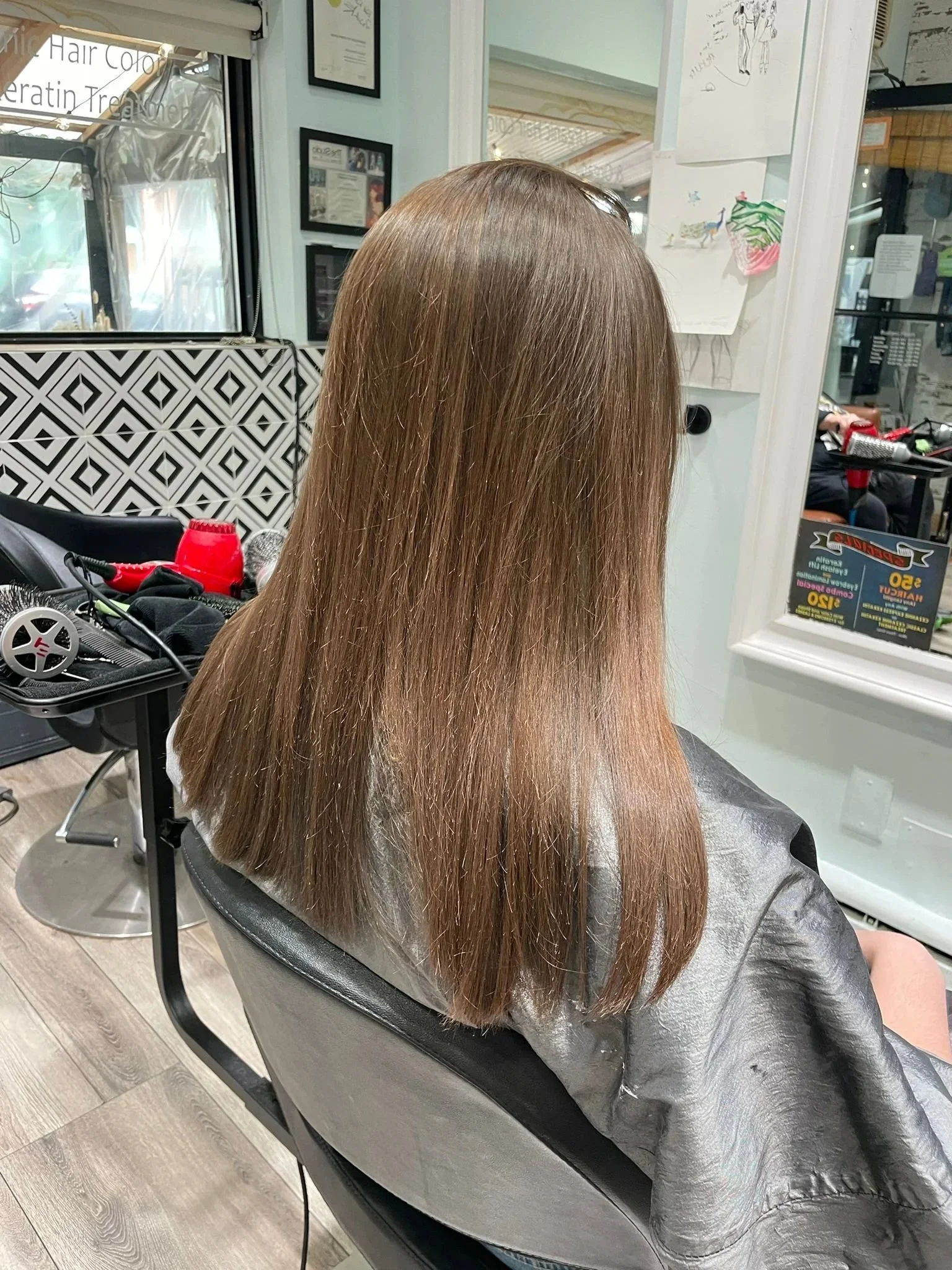 Back view of a client with long, straight light brown hair seated in a salon chair.