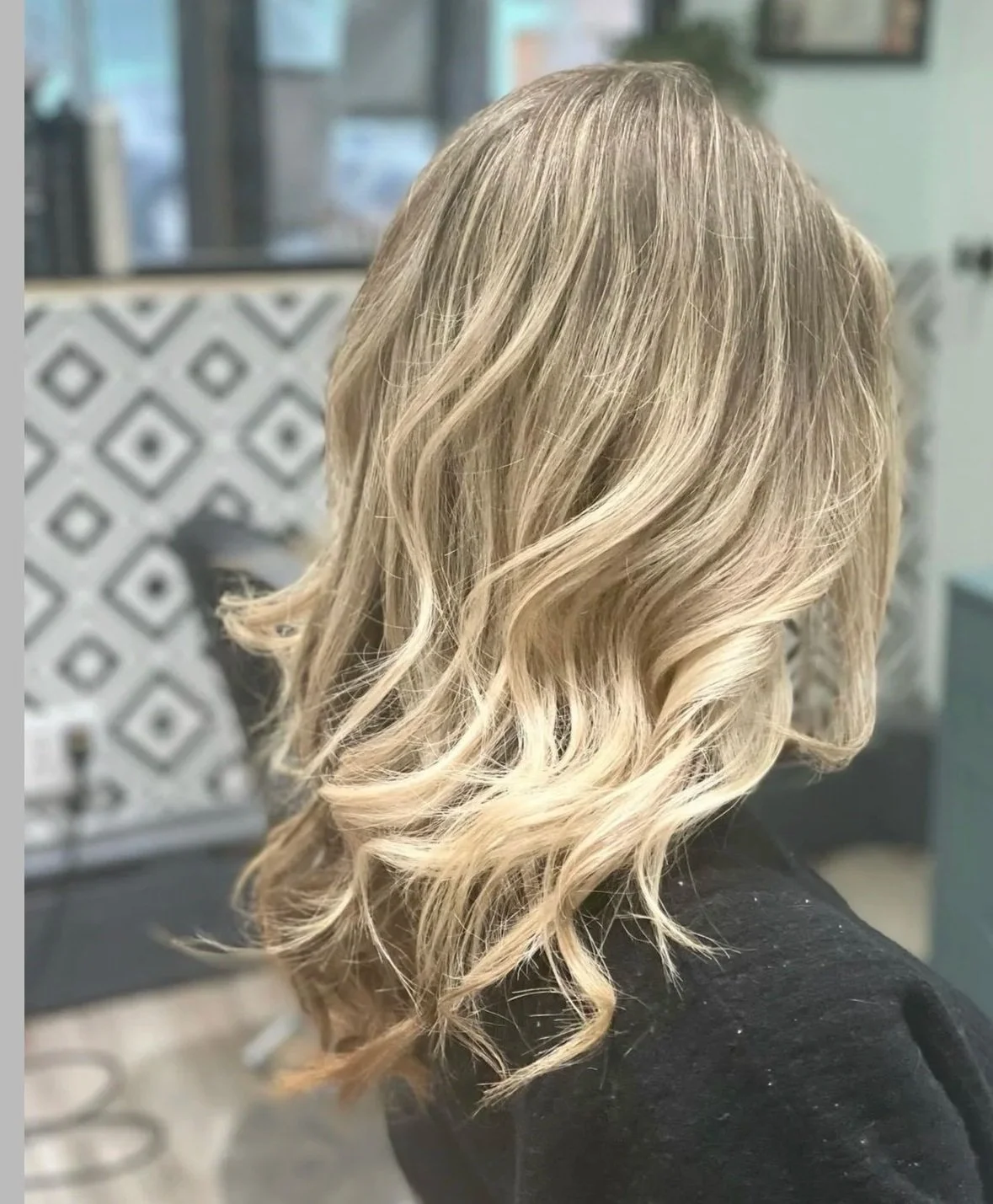 Blonde shoulder-length wavy hairstyle with layered curls in a salon