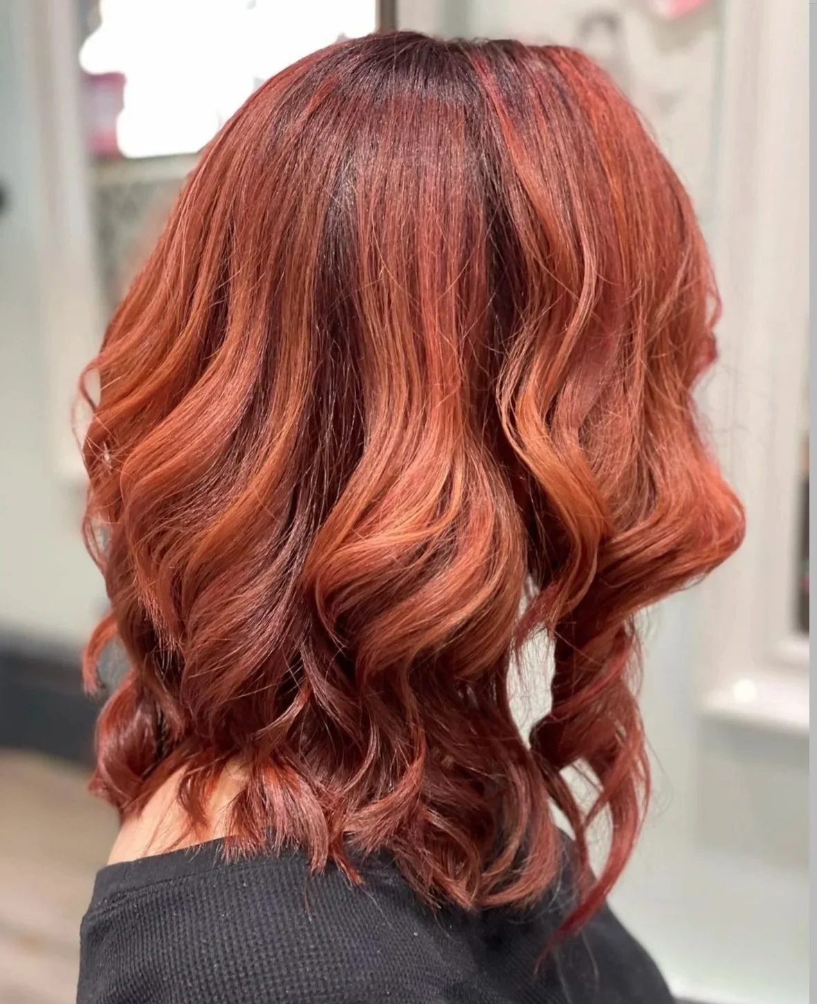 Back view of medium-length copper-red wavy hair with layered curls