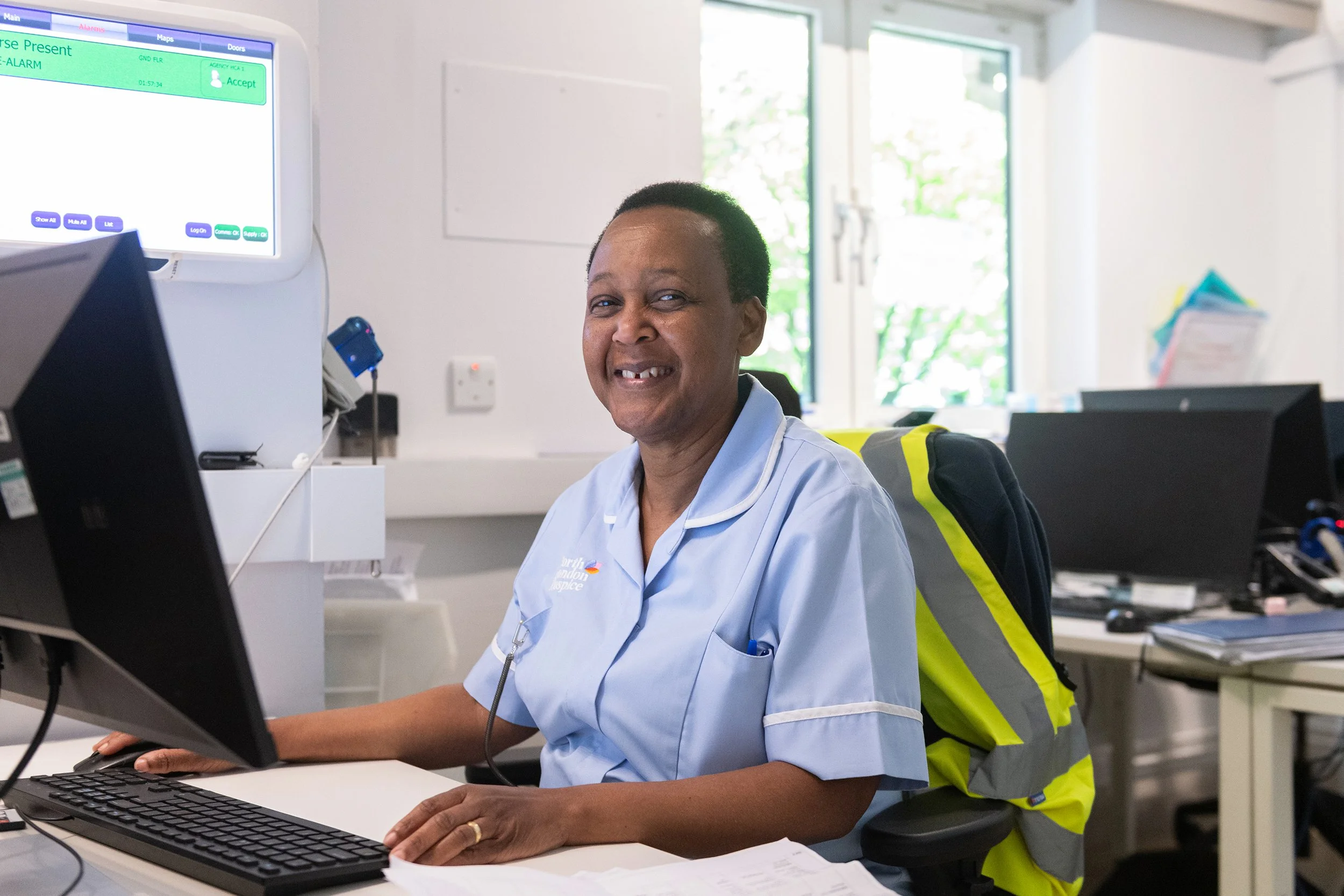 A nurse posing for her portrait at her desk