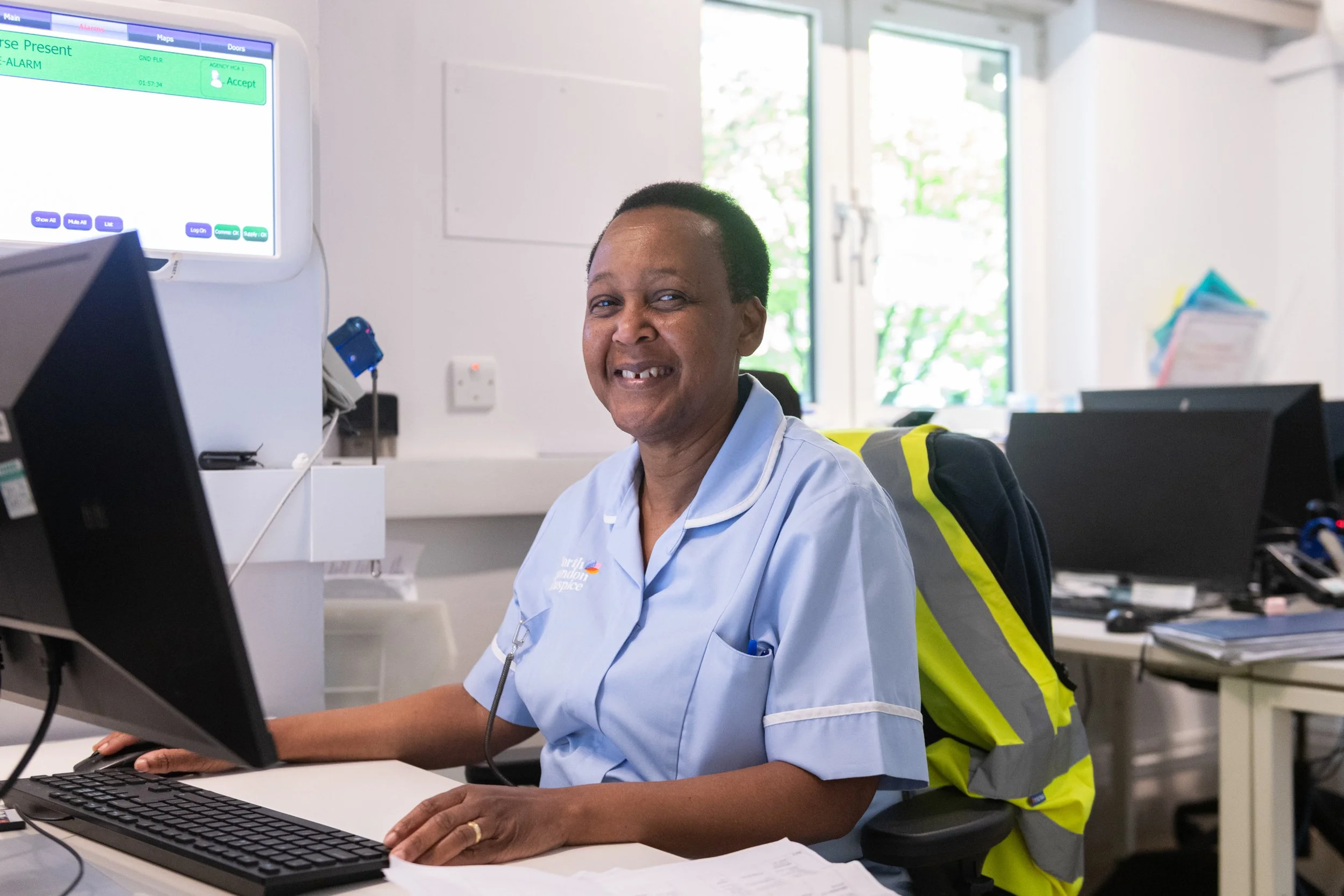 A nurse posing for her portrait at her desk