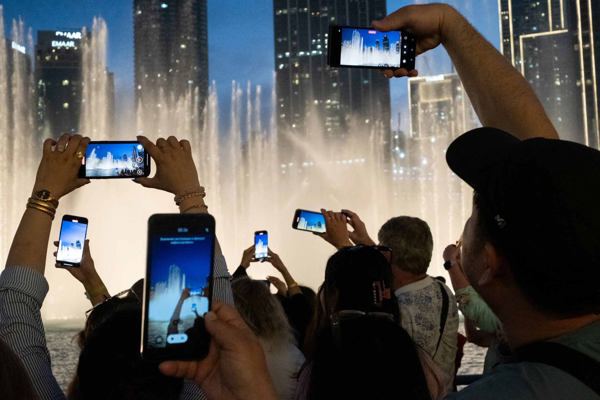 A group of tourist taking pictures of the Dubai Fountains on their mobile phones