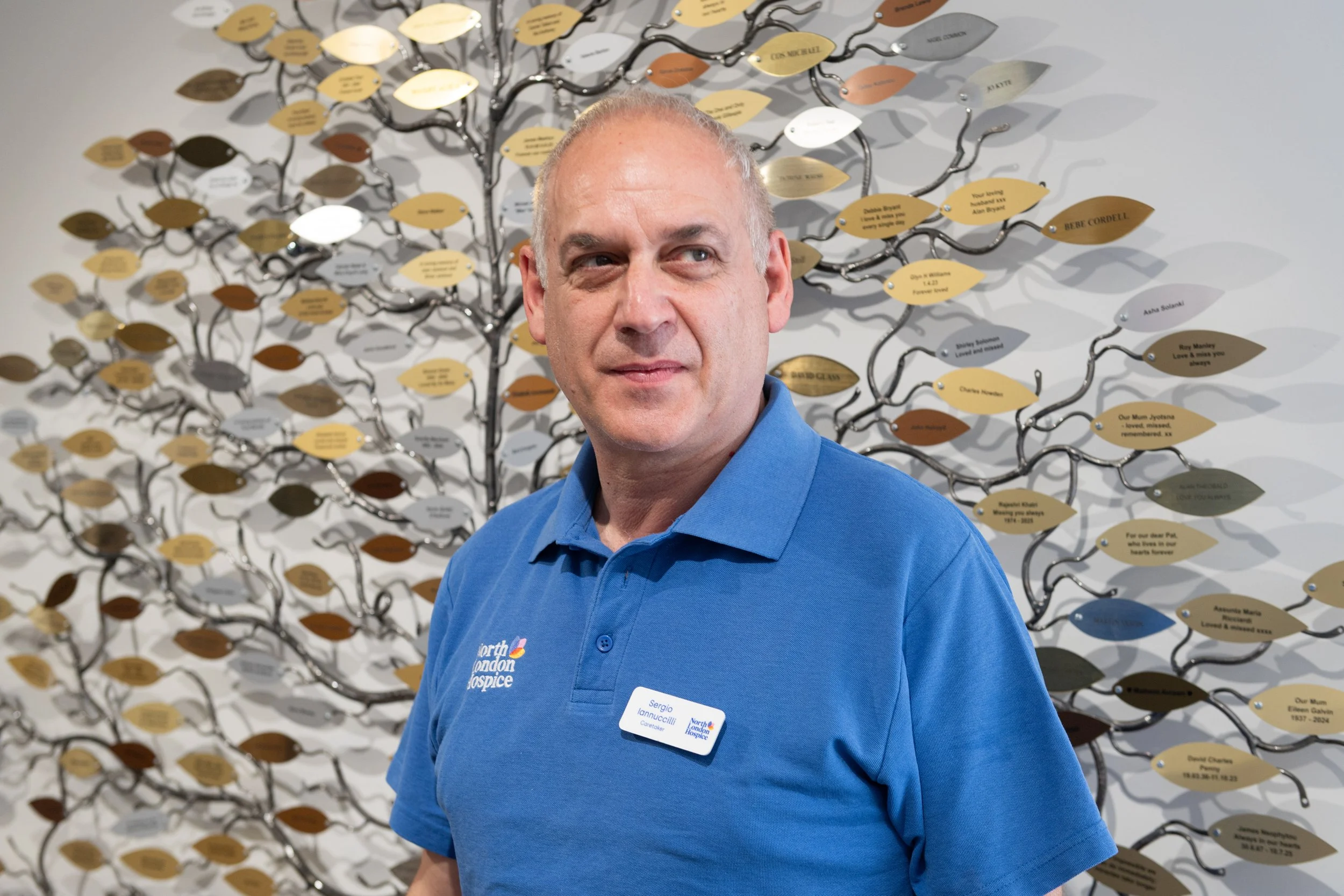 Maintenance worker posing for portrait in front of tribute tree
