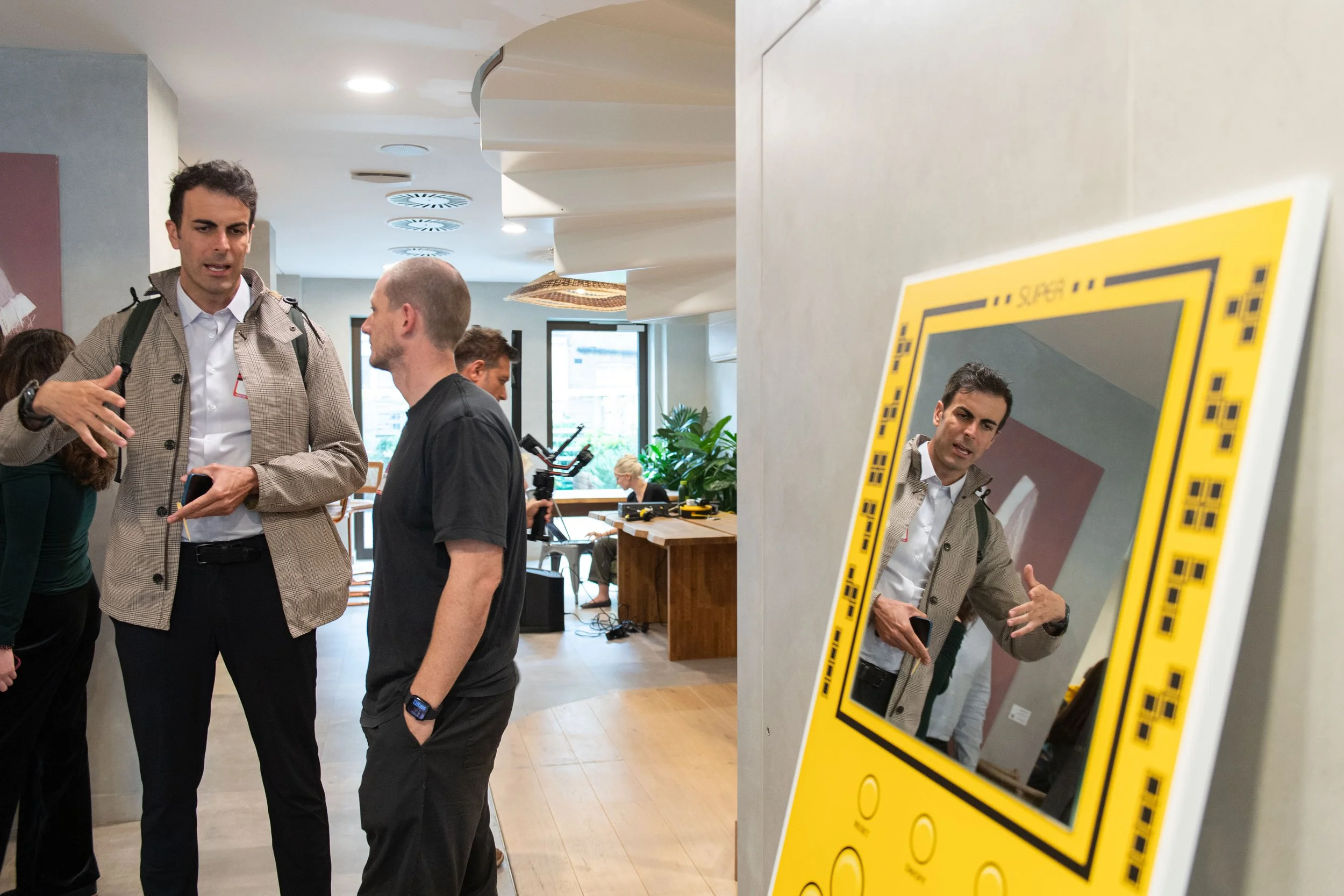 Two men in discussion, Man on the left is seen in mirror placed on the right