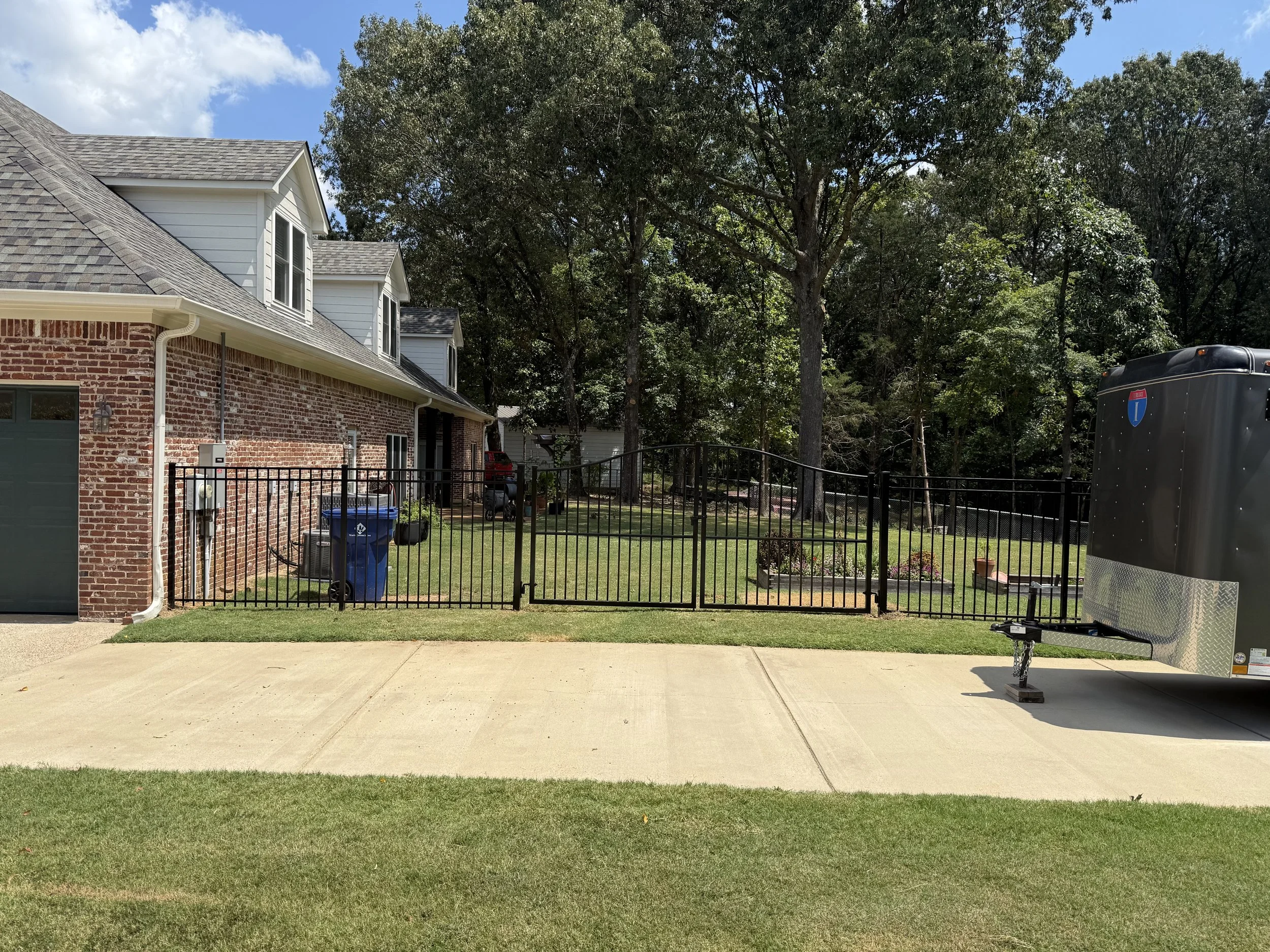 Arched aluminum driveway gate installed with matching residential aluminum fencing in Hernando, Mississippi by DeSoto Fence Co.