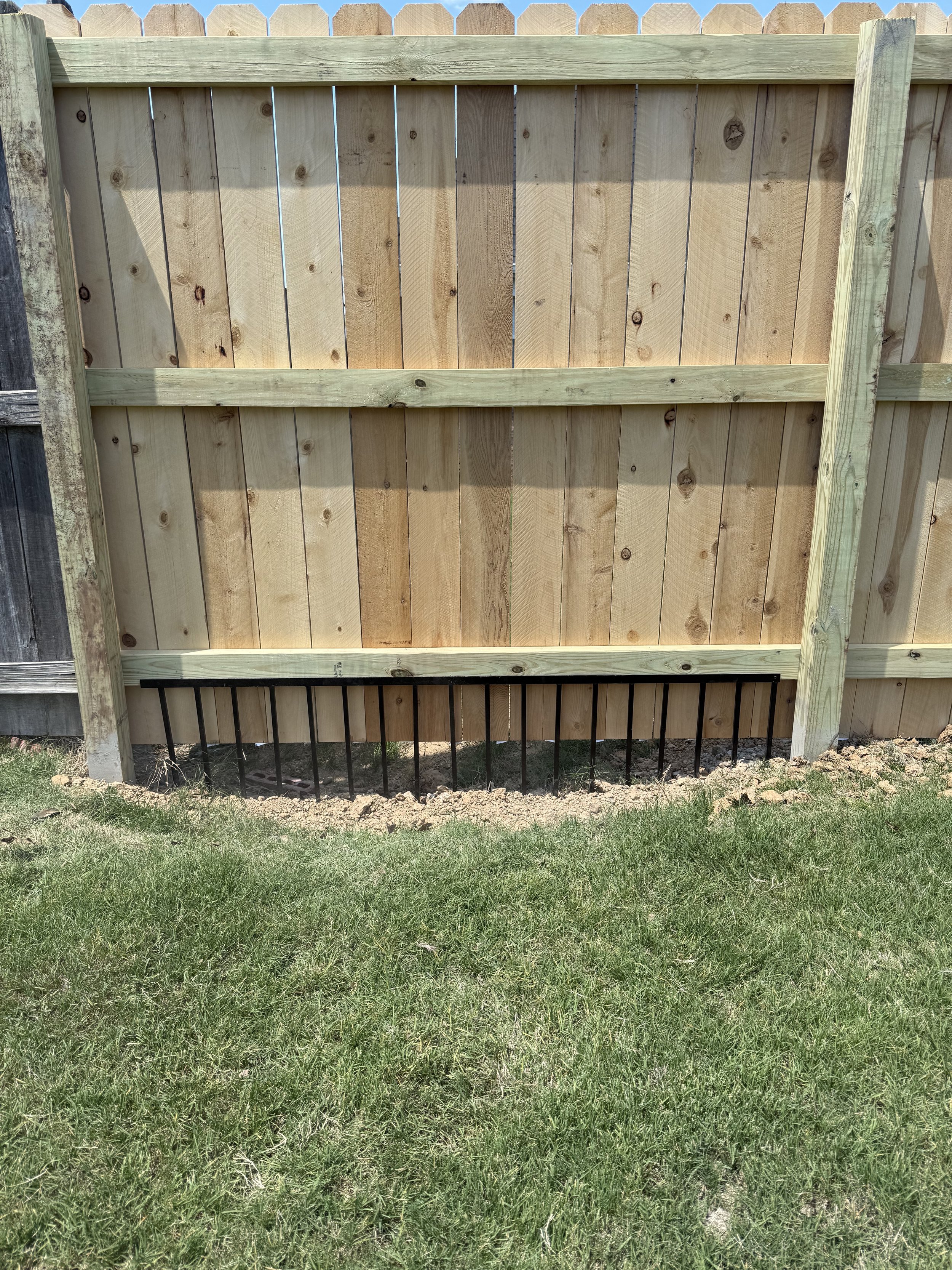 Cedar privacy fence with drainage grate for erosion control installed in Southaven, MS by DeSoto Fence Co.