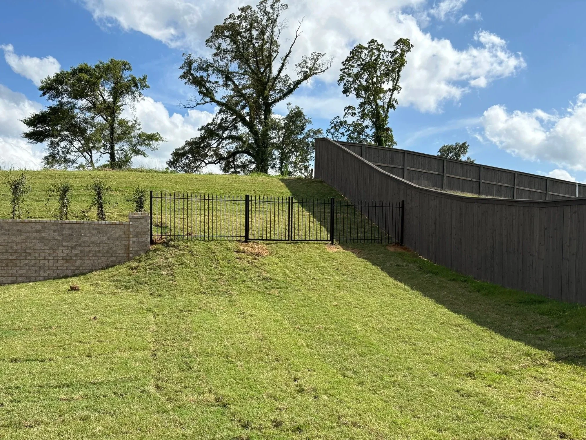 Ornamental aluminum walk gate with matching residential fencing installed on a sloped property in Olive Branch, Mississippi by DeSoto Fence Co.