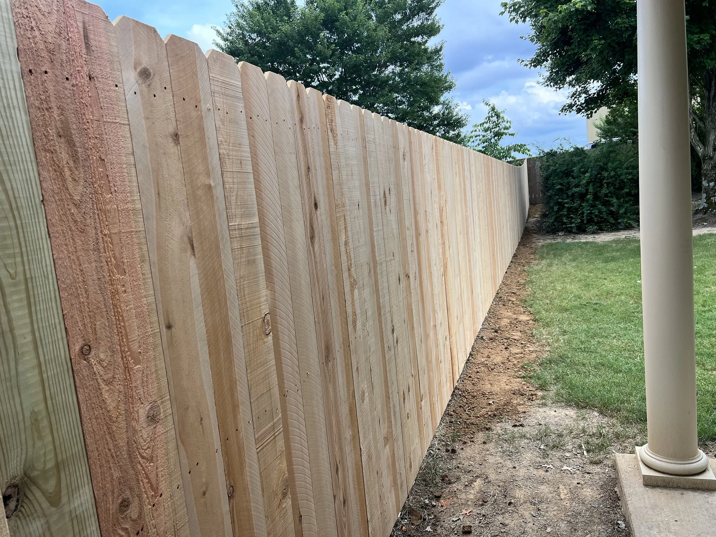 Side yard view of a cedar privacy fence in Hernando, MS. Designed for full privacy with a smooth, consistent fence line that ties cleanly into the home and surrounding yard.