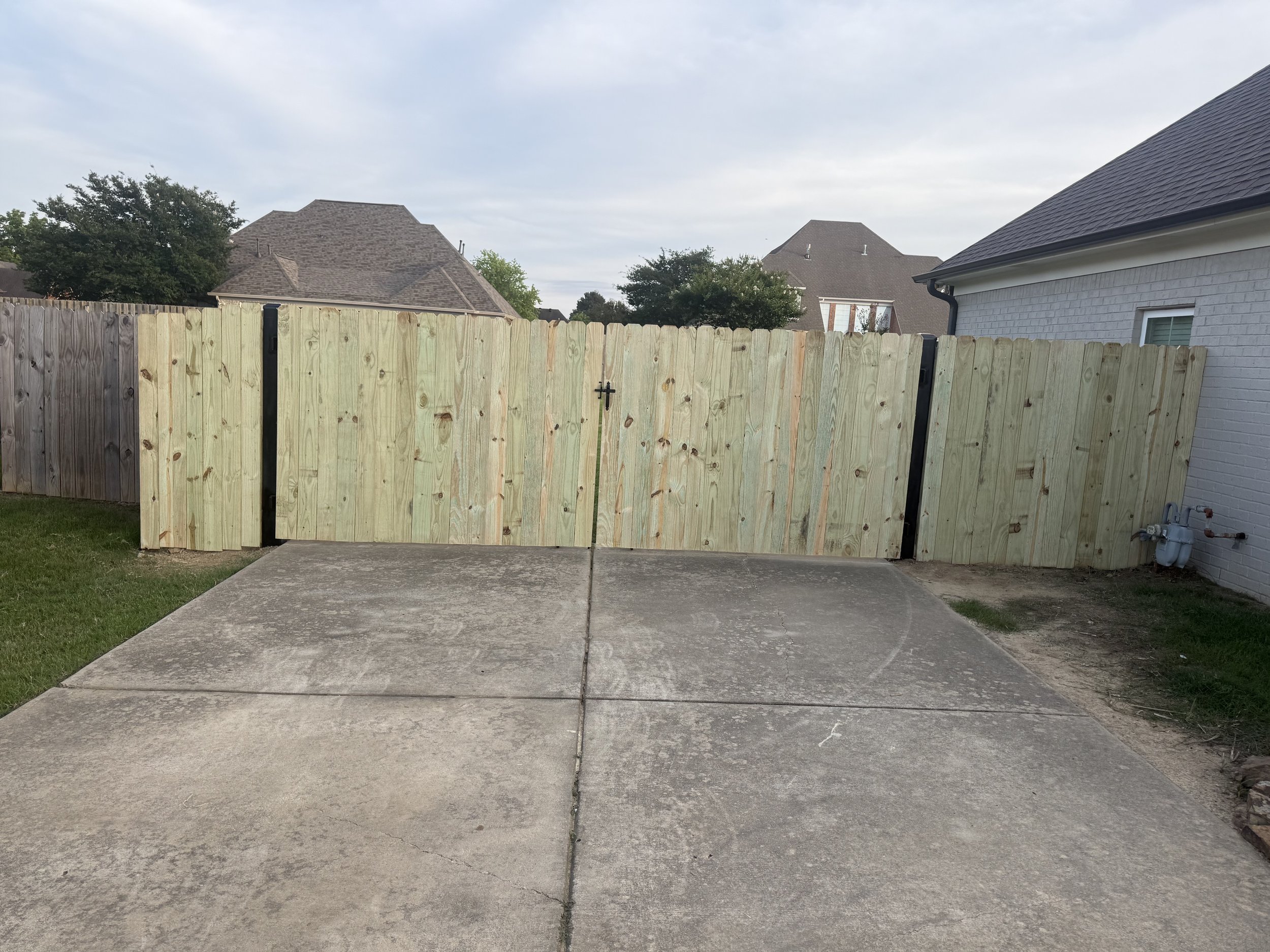 Custom metal frame driveway gates with pine privacy pickets installed in Hernando, MS for lasting durability, security, and a clean wood appearance by DeSoto Fence Co.