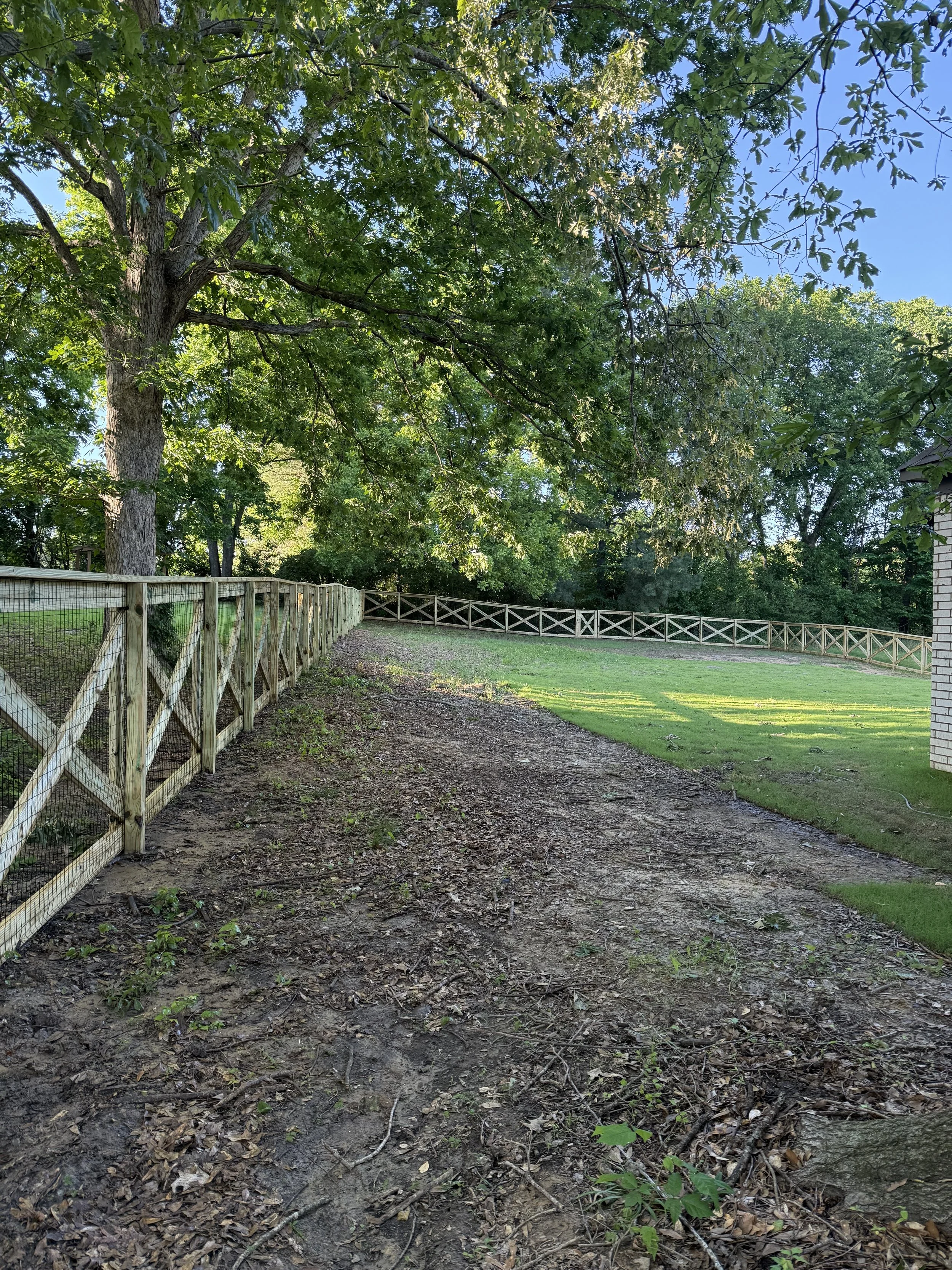 Full property view of a custom crossbuck fence with black wire in Olive Branch, MS. Designed to provide boundary control while maintaining an open and natural look.