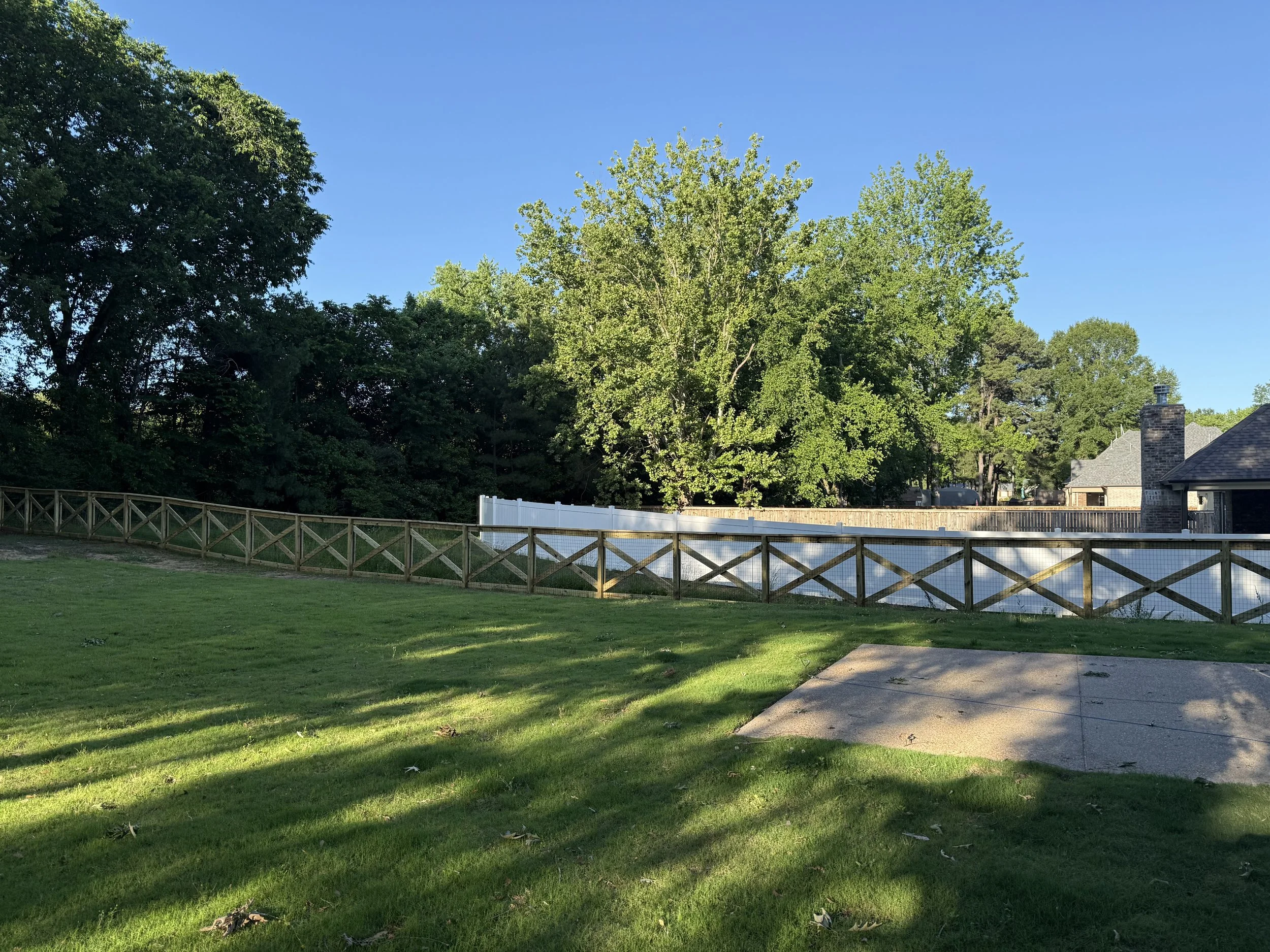 Large yard enclosed with a crossbuck and wire fence in Olive Branch, MS. This style allows visibility across the property while still providing a defined perimeter.